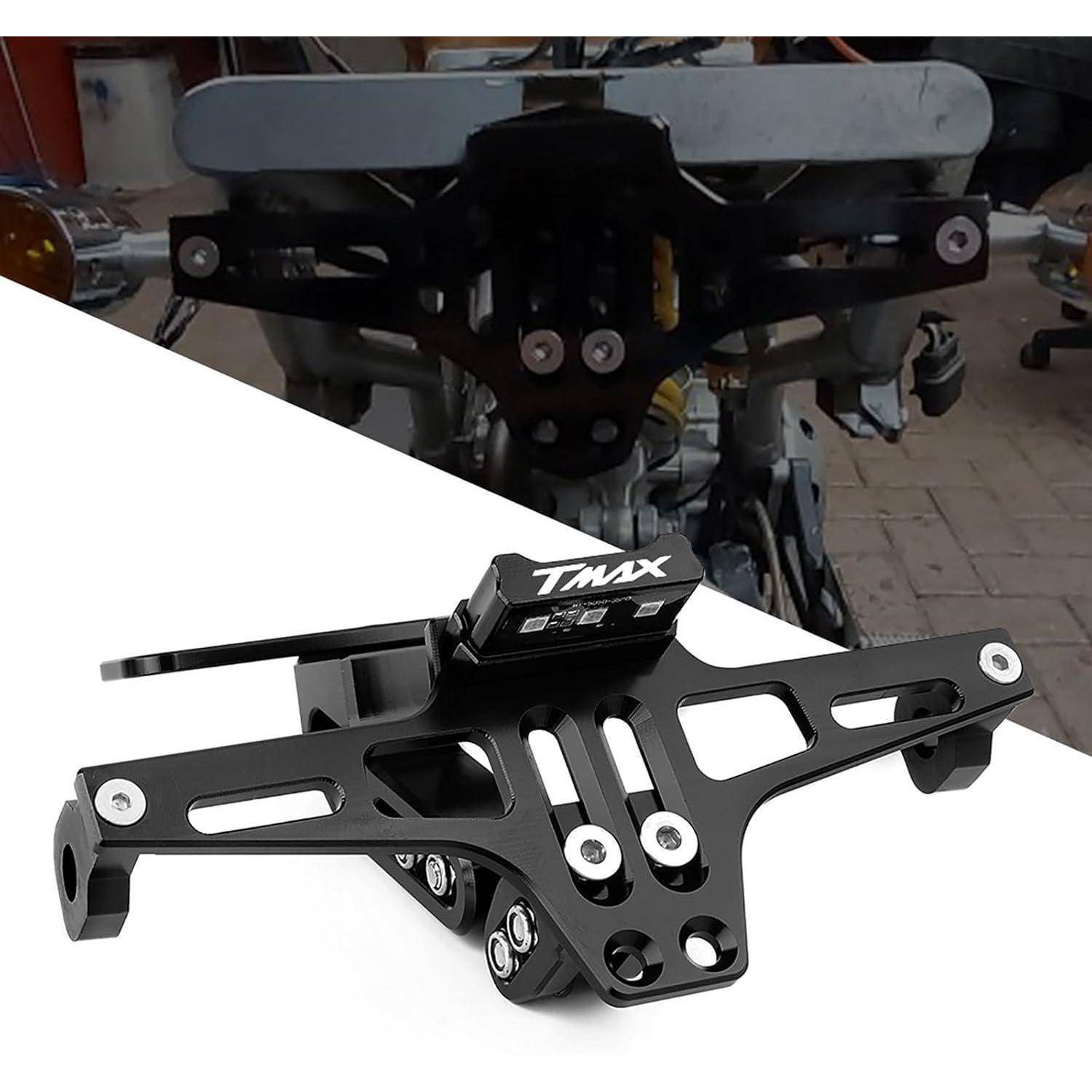 Schwarze TMAX-Motorrad-Kennzeichenhalterung und Schutzblech-Befestigung auf weißem Hintergrund, mit unscharfem Installationsbeispiel im Hintergrund.