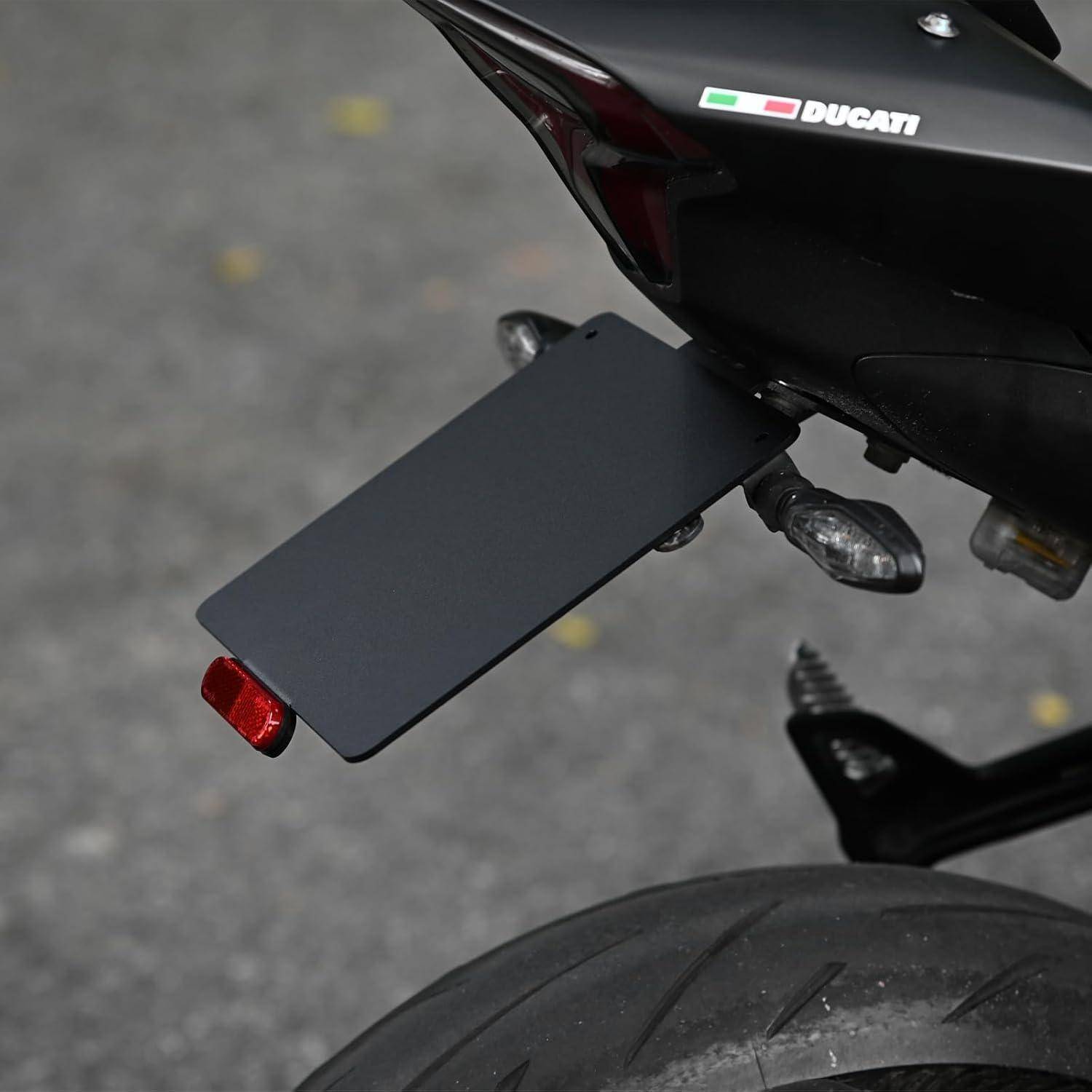 Nahaufnahme des Hinterteils eines Ducati-Motorrads mit einer leeren Kennzeichenhalterung, Blinklicht und Hinterreifen, die gegen das Pflaster sichtbar sind.
