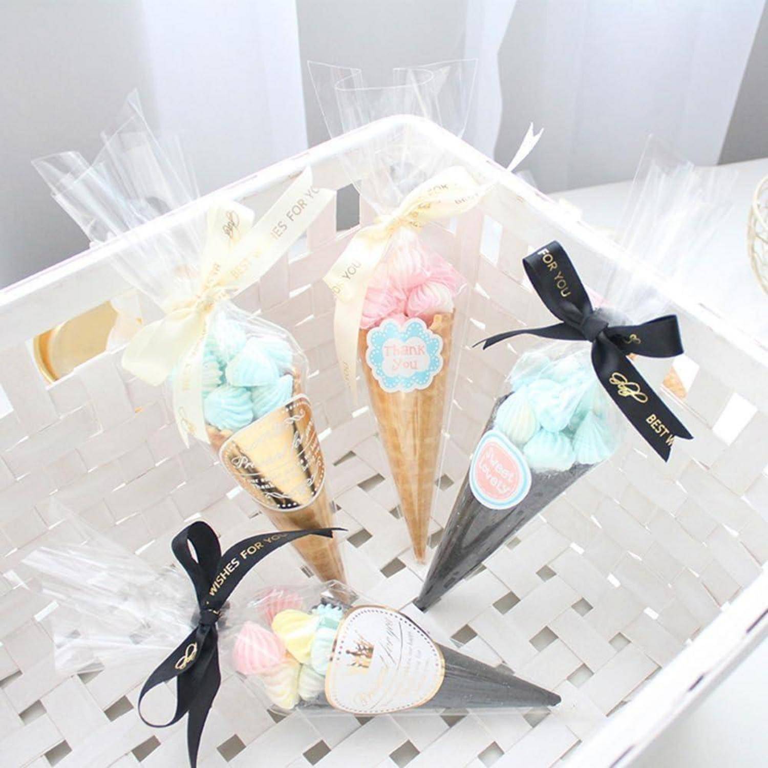 Geschenkkörbchen mit pastellfarbenen Marshmallow-Süßigkeiten, angeordnet in dekorativen Eistüten-Verpackungen mit Schleifen und Etiketten in einer weißen Schachtel.