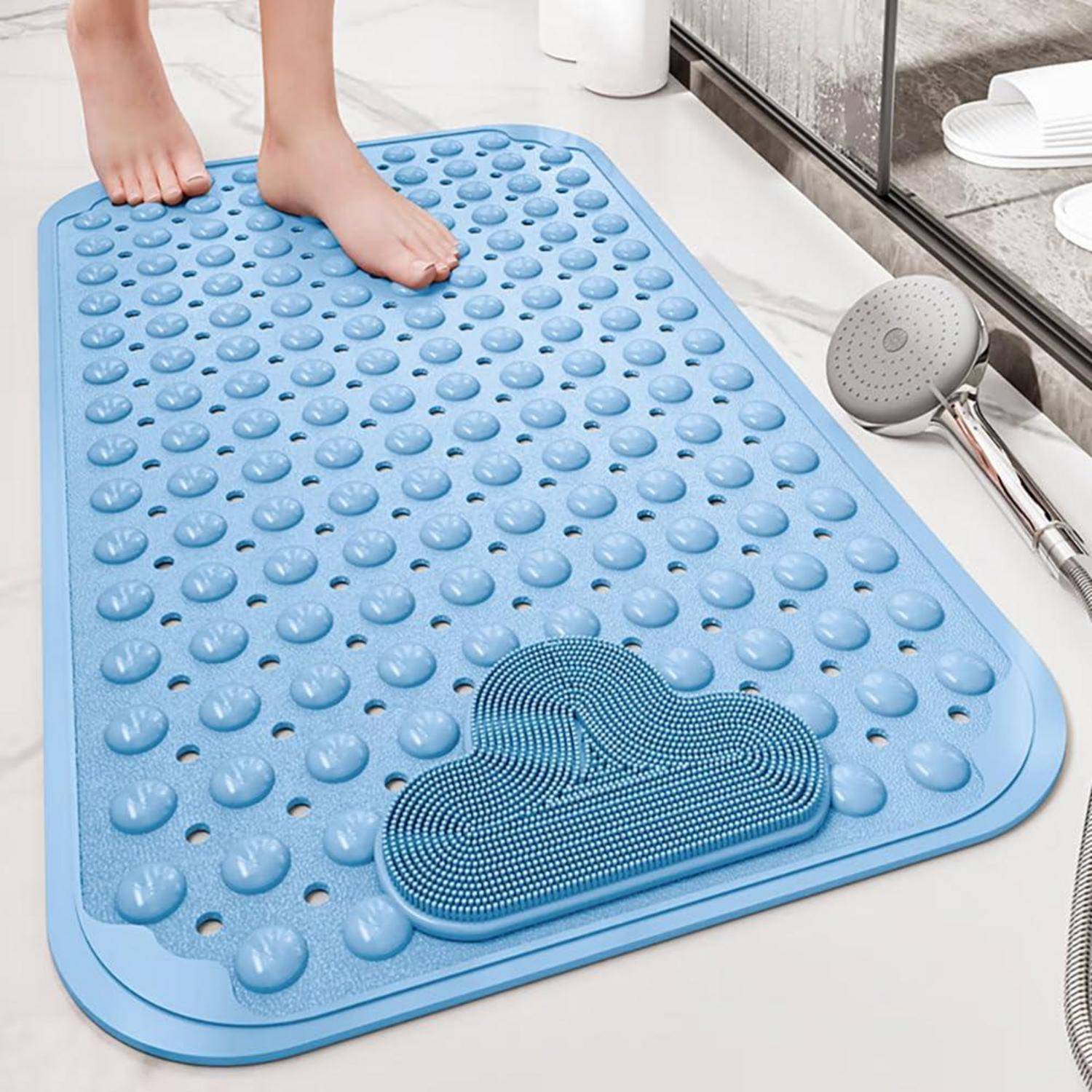 Person, die auf einer blauen strukturierten Badematte mit erhabenen Noppen und einem Fußschrubber steht, neben einer Handbrause im Badezimmer.
