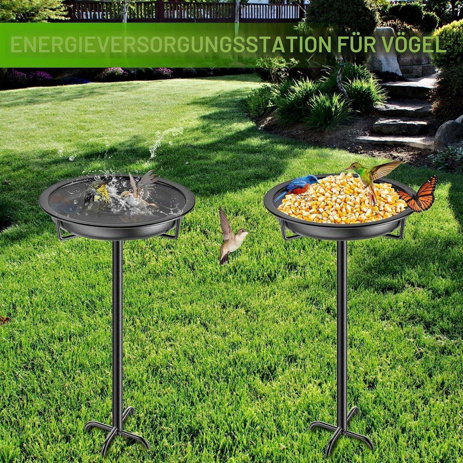 Zwei Vogelfütterungsstationen im Garten, eine mit spritzendem Wasser und eine gefüllt mit Vogelfutter, beschriftet mit „ENERGIEVERSORGUNGSSTATION FÜR VÖGEL