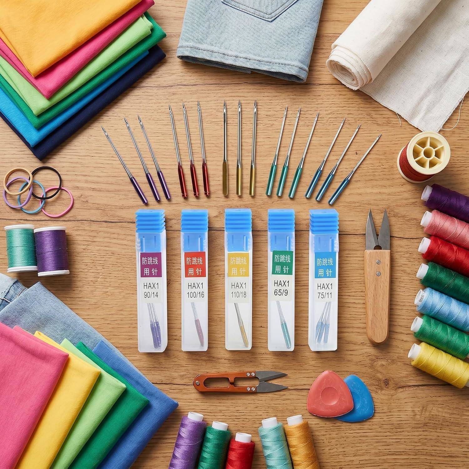 Flachaufnahme von Nähzubehör: farbige Stoffe, Fäden, Nadeln, Scheren, Fingerhüte und beschriftete Stricknadeln auf einem Holztisch angeordnet.