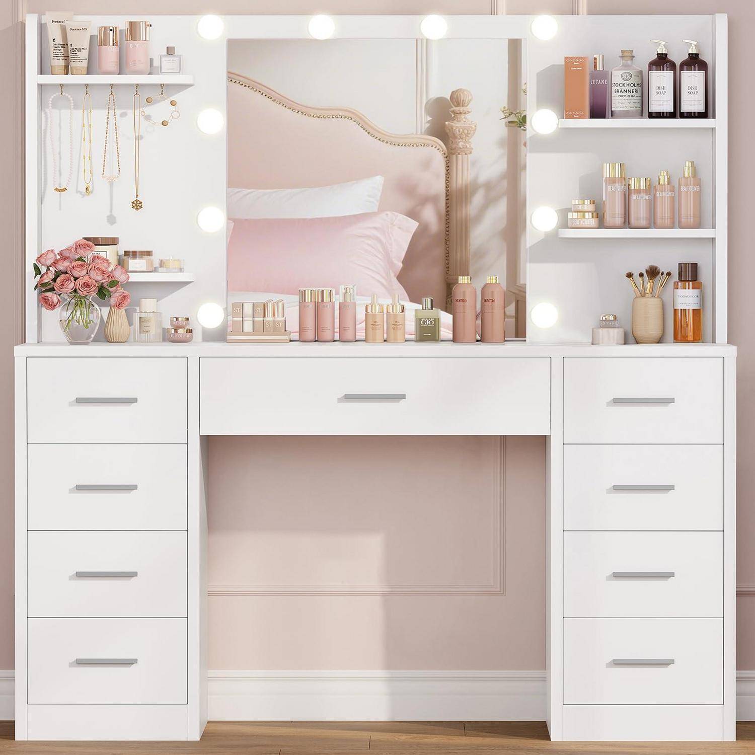 Weiße Kommode mit Spiegel, Schubladen und Regalen, die Kosmetik, Parfüm, Schmuck, Pinsel, Blumen und Deko in einem sanften rosa Schlafzimmer ordentlich präsentieren.