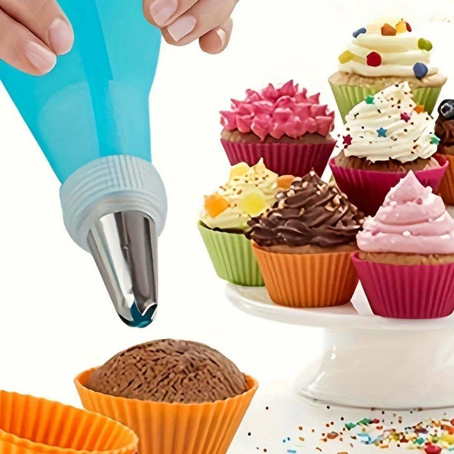 Eine Hand spritzert blaue Glasur aus einem Spritzbeutel auf einen Schokoladen-Cupcake, während im Hintergrund ein Ständer mit dekorierten Cupcakes zu sehen ist.