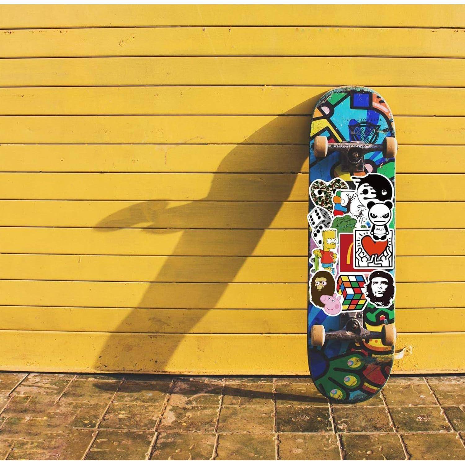 Ein buntes Skateboard lehnt aufrecht an einer gelben Holzwand und wirft einen langen Schatten auf den Boden.