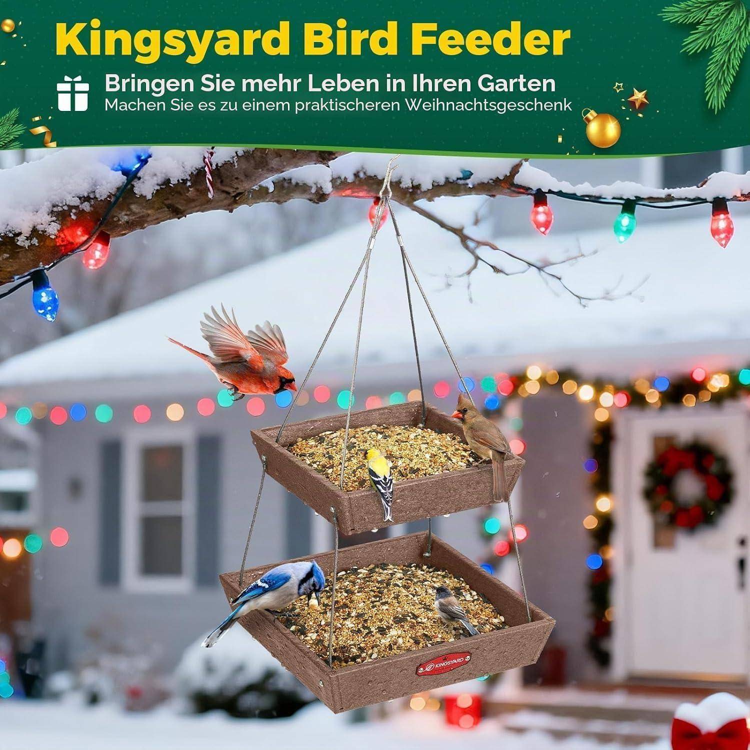 Kingsyard Vogelfutterhaus hängt draußen in einem schneebedeckten Garten, mit mehreren Vögeln, die von zwei übereinander gestapelten Tabletts fressen; deutscher Anzeigentext lautet „Bringen Sie mehr Leben in Ihren Garten