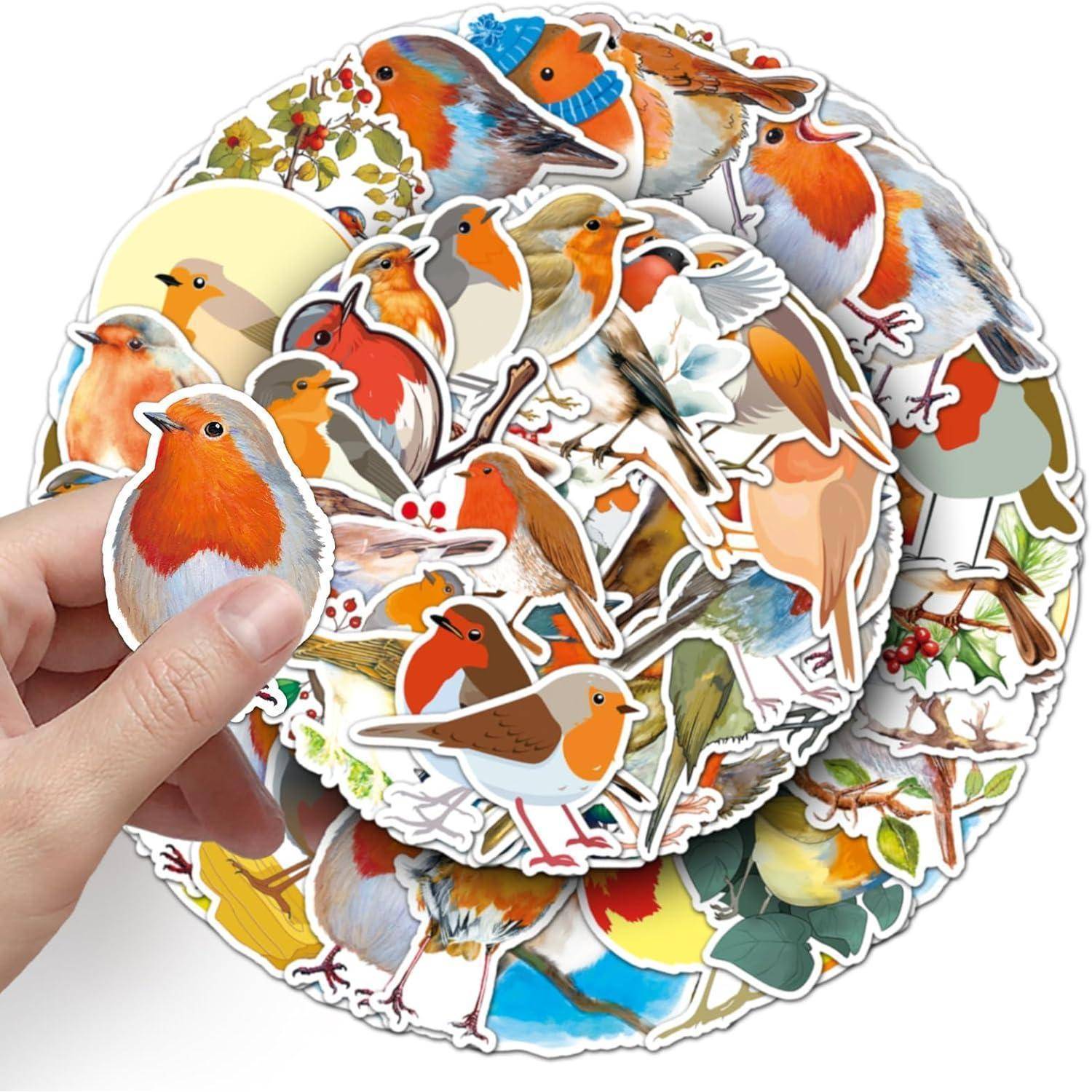 Eine Hand hält einen Stapel von ausgestanzten Vogel-Aufklebern, hauptsächlich Rotkehlchen und andere bunte Vögel mit Blüten- und Naturszenen.