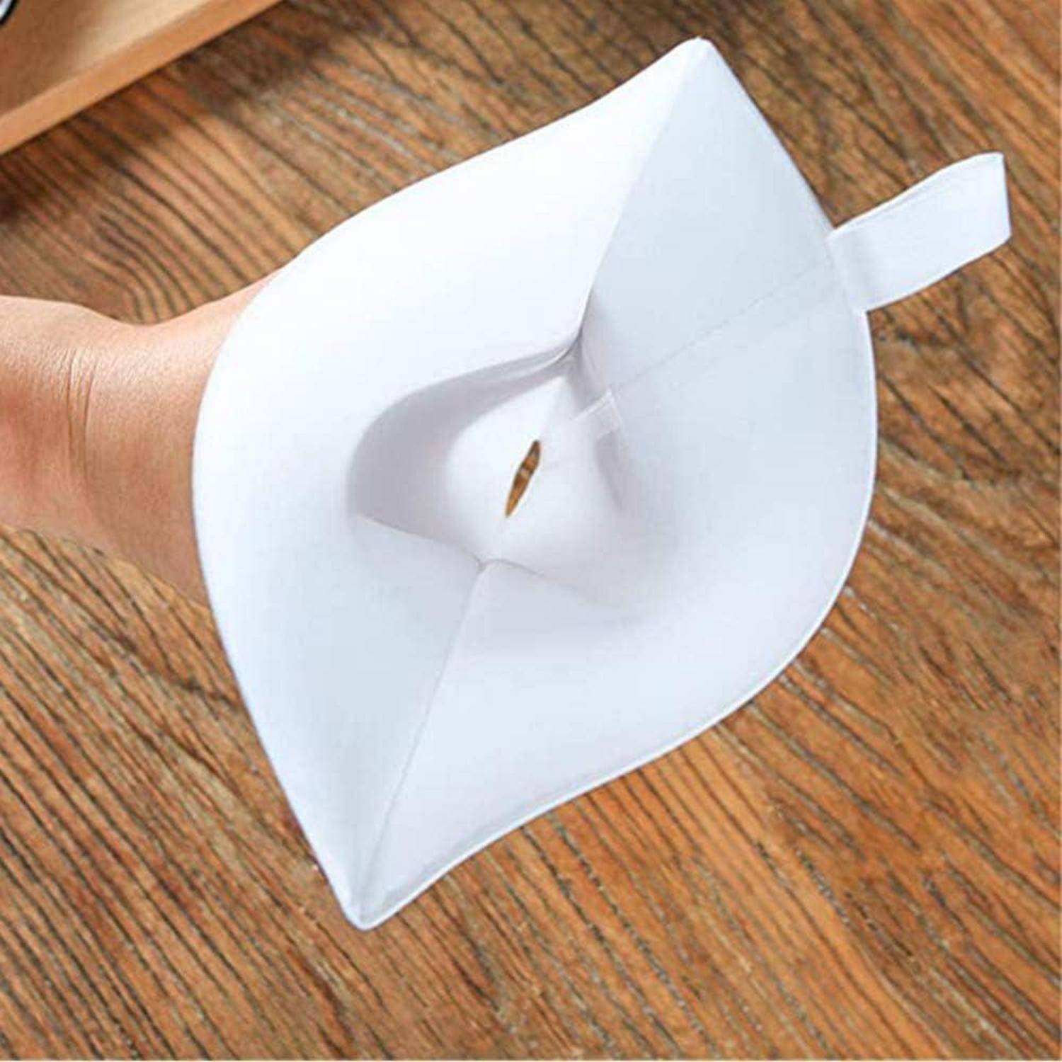 Hand, die einen weißen Papierkegel-förmigen Filter oder Trichter über einer Holzoberfläche hält.