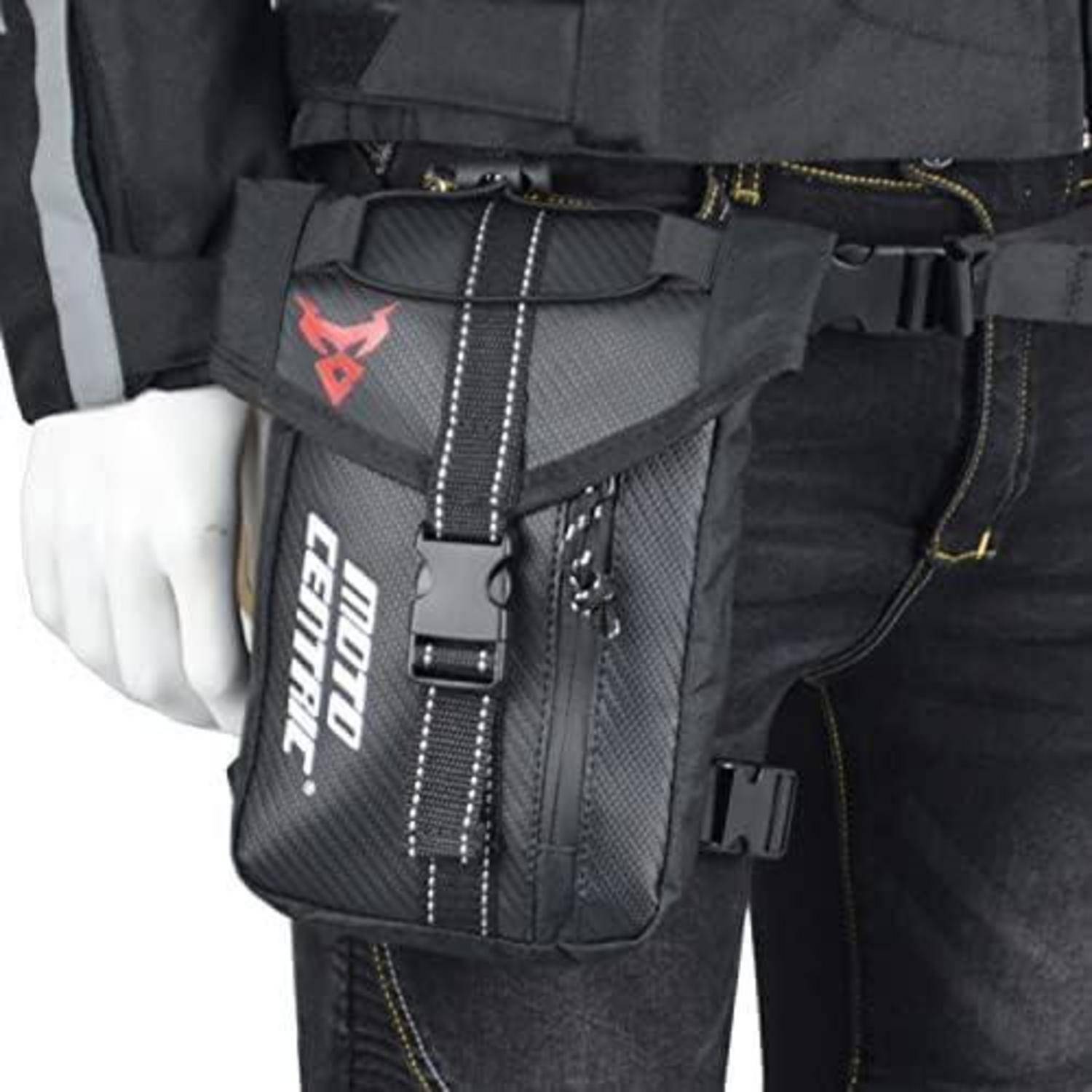 Schwarze MotoCentric-Oberschenkeltasche an das Oberschenkel einer Person geschnallt, mit Schnallenverschluss und rotem Logo.