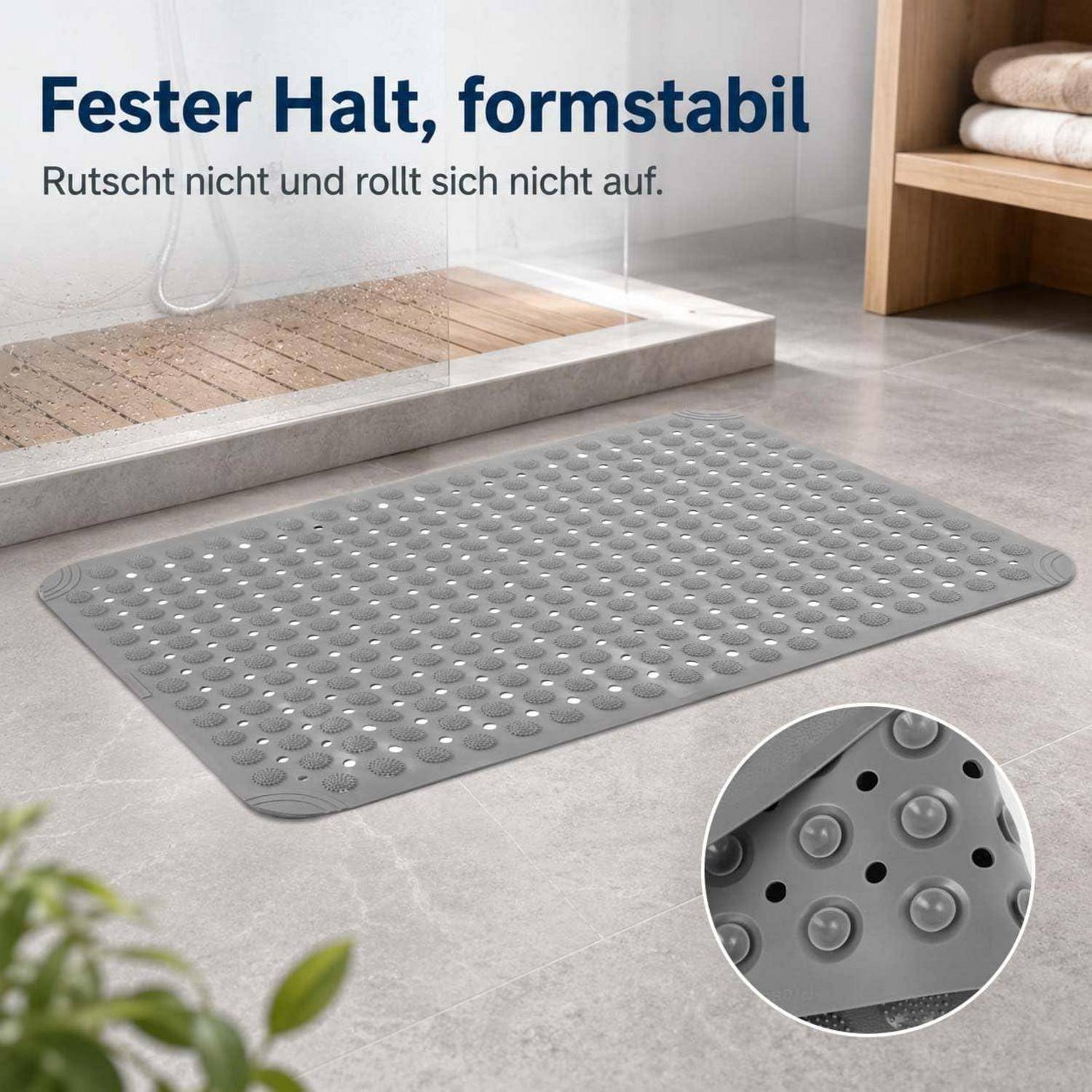 Grauer rutschfester Badteppich mit erhabenen Saugnäpfen im Badezimmer, beschriftet mit „Fester Halt, formstabil