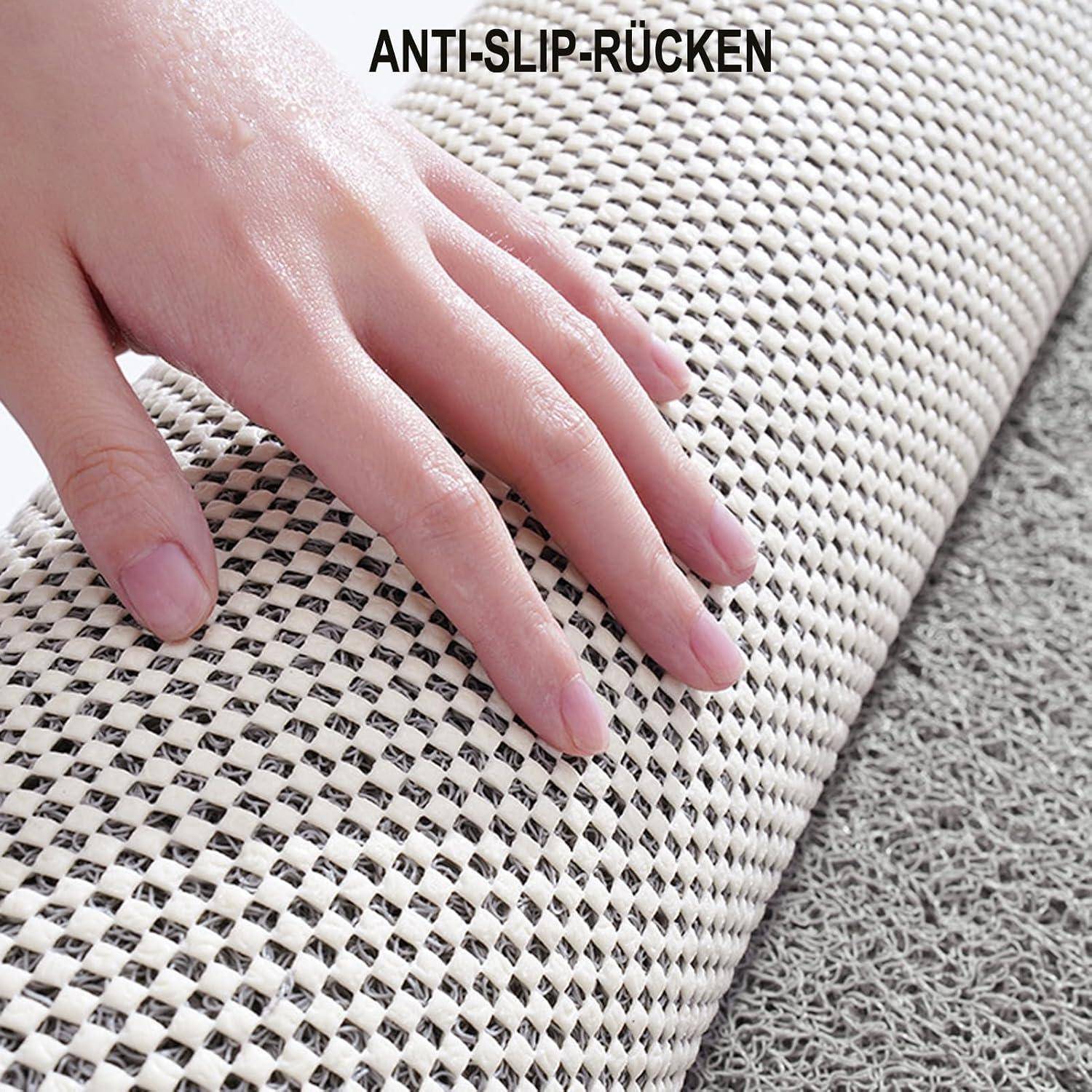 Hand drückt auf eine strukturierte Teppichrückseite mit der Aufschrift „ANTI-SLIP-RÜCKEN