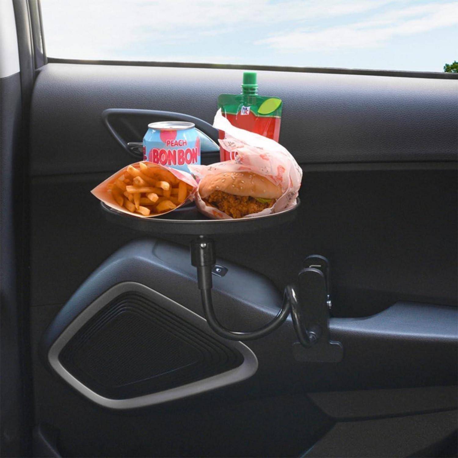 Autotürmontiertes Tablett mit Pommes, einem Burger, einem Pfirsich-BonBon-Getränk und einer Flasche, das ein provisorisches Essensset im Auto zeigt.