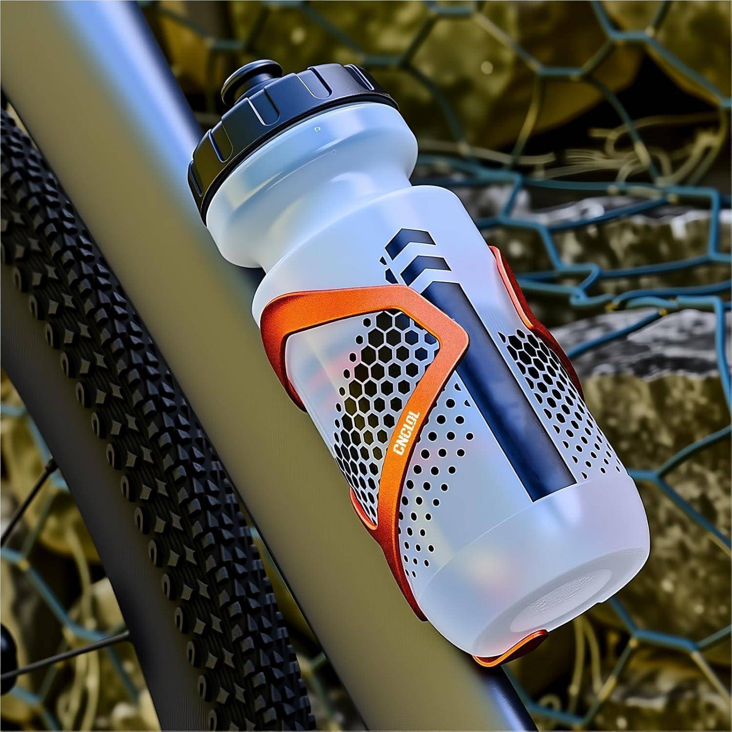 Weiße und orange Wasserflasche in einem Fahrradrahmenhalter montiert, mit schwarzem Verschluss und perforierten Griffpaneelen.
