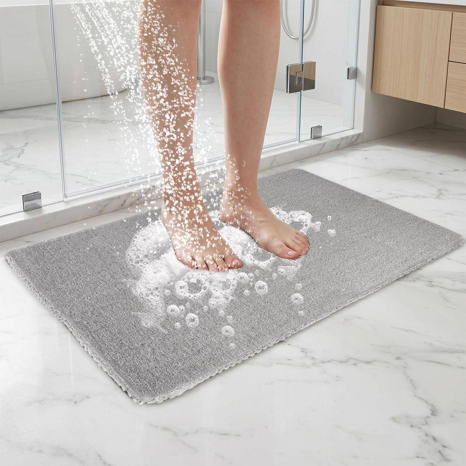 Füße stehen auf einer grauen Badematte, während Wasser herabspritzt und einen rutschfesten Dusch­teppich im Badezimmer zeigt.