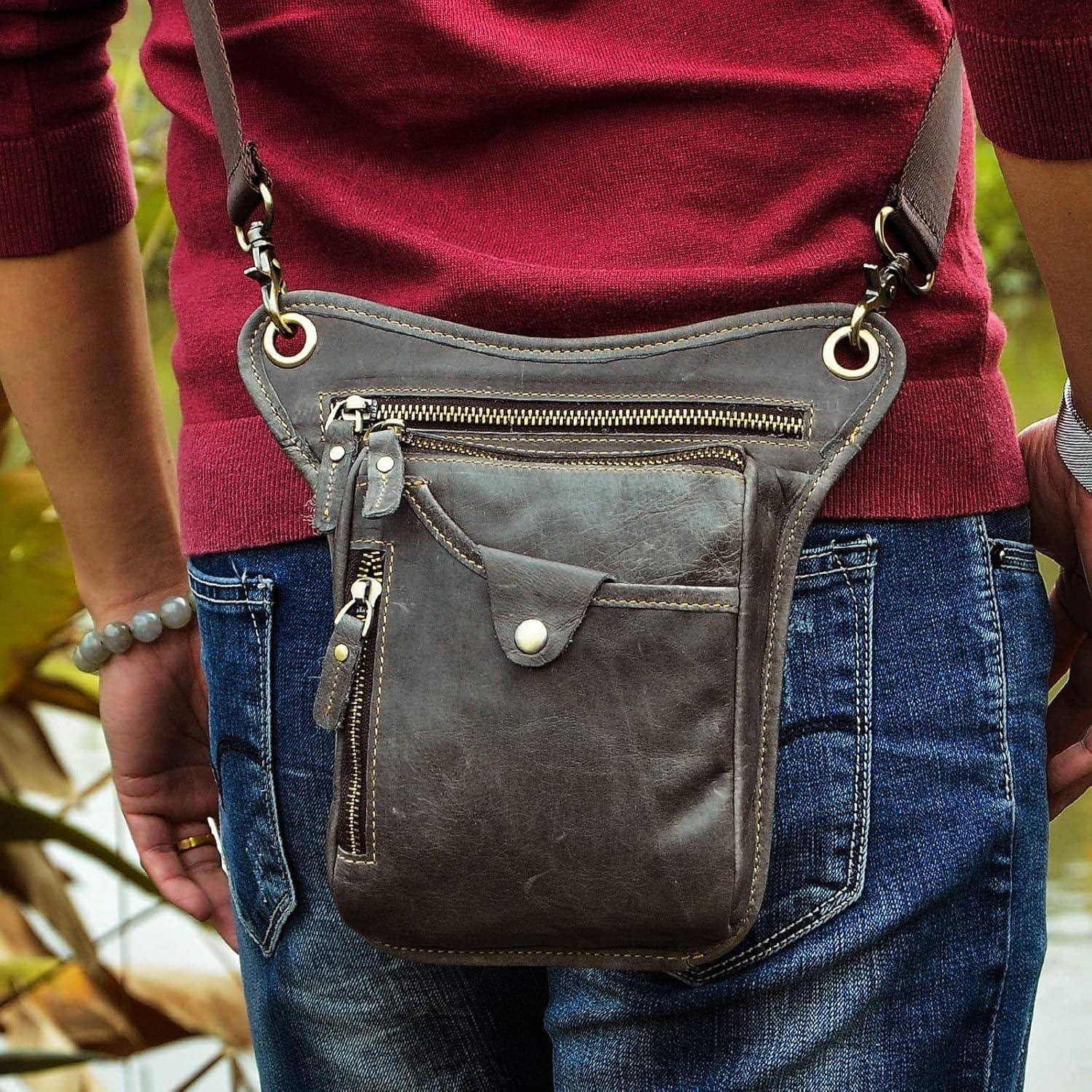 Nahaufnahme einer Person, die eine graue Lederhüfttasche mit Schultergurt über einem kastanienbraunen Pullover und blauen Jeans trägt.
