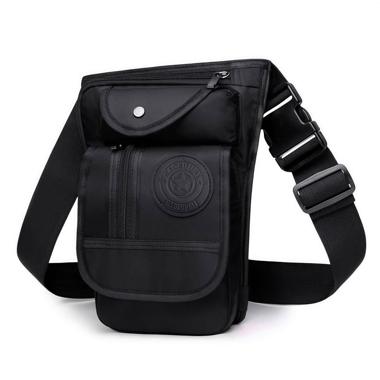 Schwarze Schultertasche mit verstellbarem Riemen, Frontklappentasche, Reißverschlussfächern und rundem Logo-Patch, dargestellt auf weißem Hintergrund.