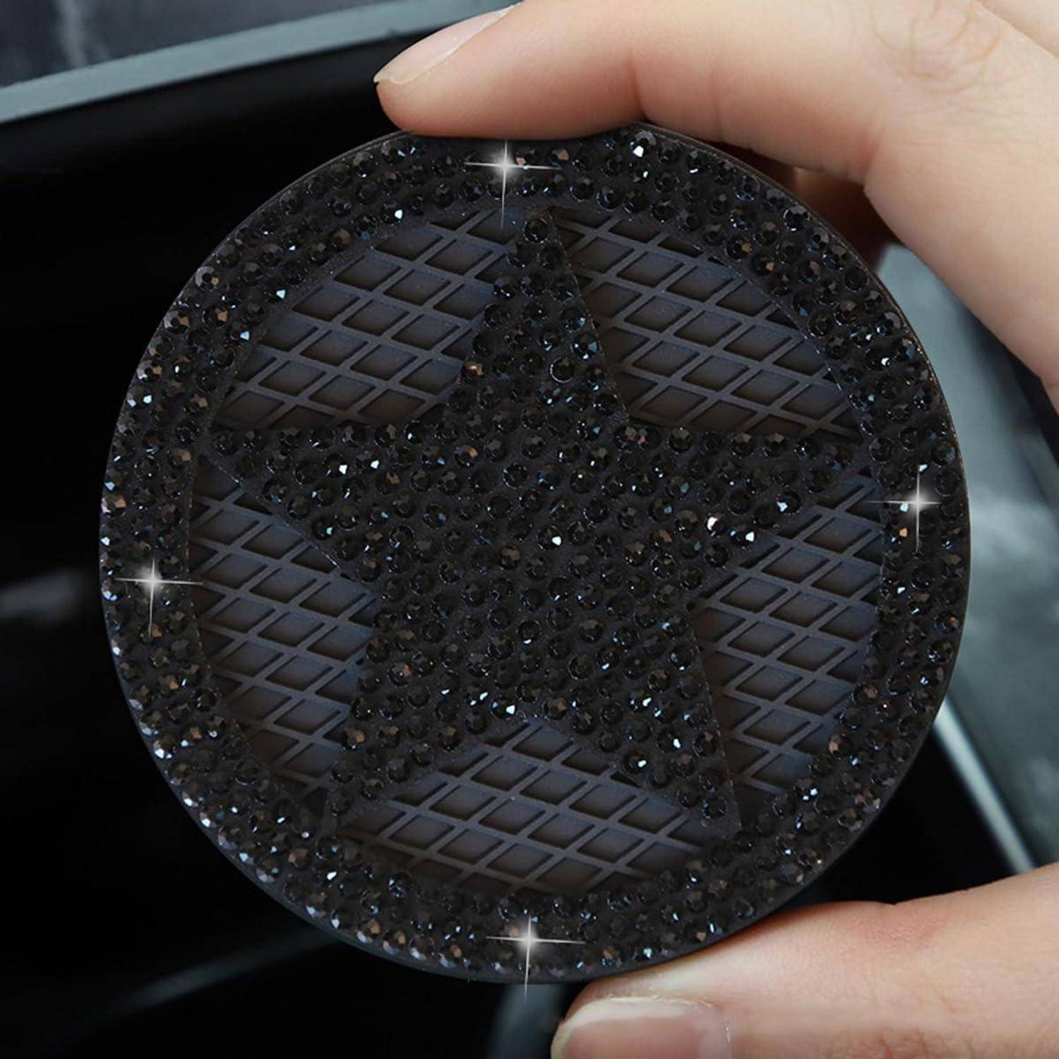 Nahaufnahme eines runden, dunklen, mit Strass bedeckten Ornaments oder Compacts mit einem sternförmigen Design, das zwischen den Fingern gehalten wird.
