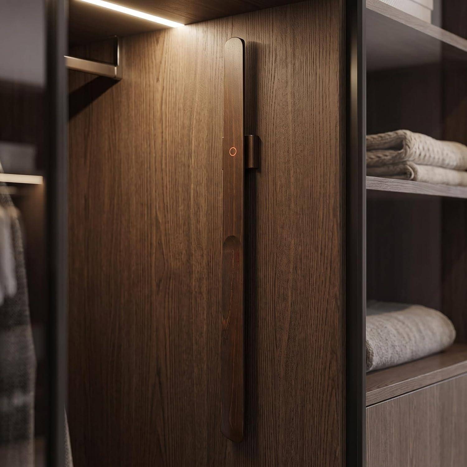 Moderner Holzgarderobenschrank mit hohem Griff und offenen Regalen, die gefaltete Handtücher halten, beleuchtet von warmem Oberlicht.