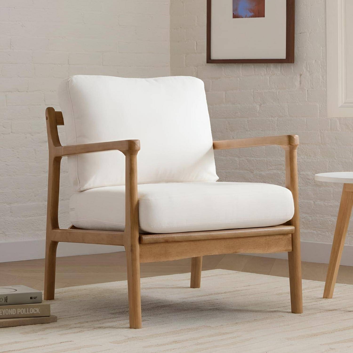 Holzstuhl mit weißem Kissen in einem minimalistischen Wohnzimmer, neben einem kleinen Beistelltisch und gerahmter Wandkunst.