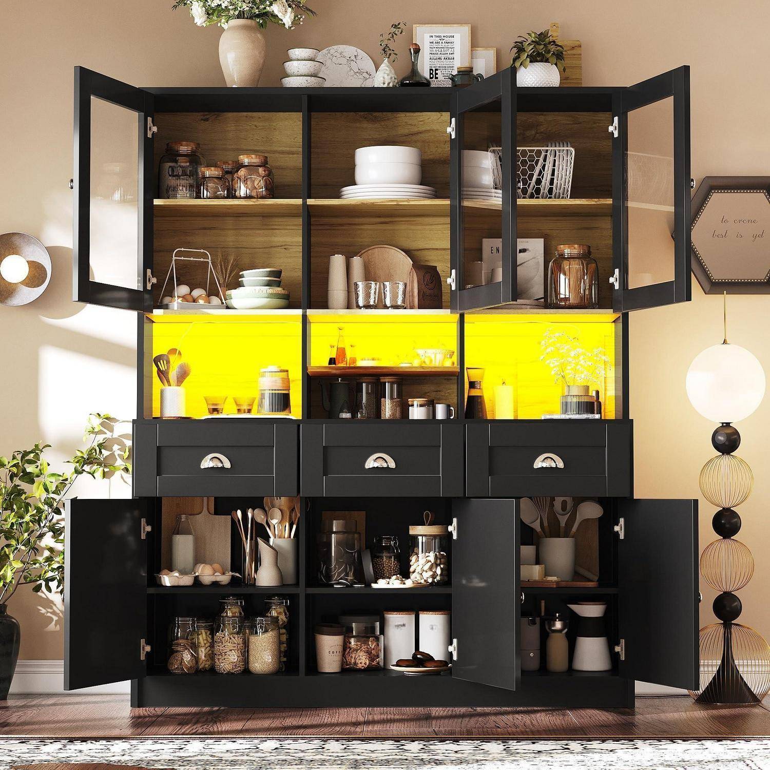 Schwarzer Küchenschrank mit offenen Glastüren, die Geschirr, Gläser und Kochutensilien ausstellen, mit hell leuchtenden, von hinten beleuchteten gelben Regalen in einem stilvoll eingerichteten Esszimmer.
