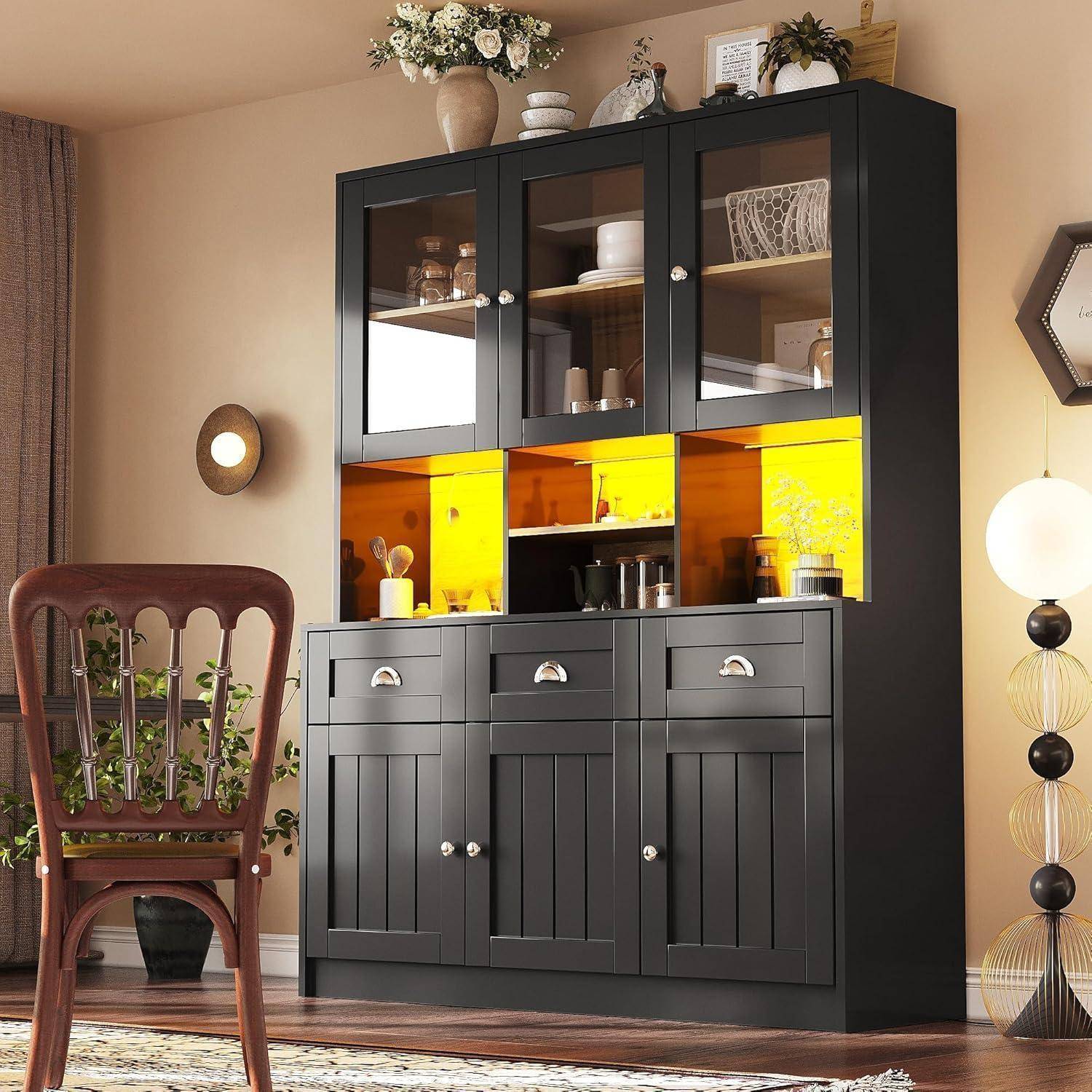 Schwarzer Vitrinenschrank mit Glastüren und gelb beleuchteten Regalen in einem Esszimmer, neben einem Holzstuhl und einer Stehlampe.