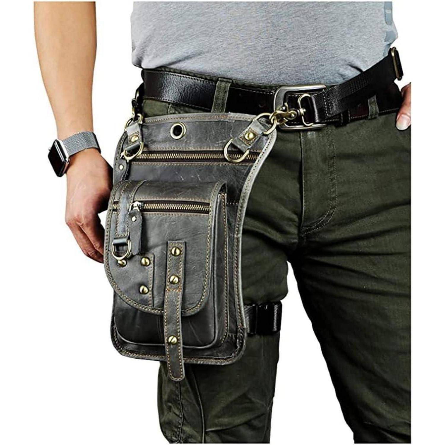 Person trägt einen schwarzen Gürtel und eine graue taktische Utility-Oberschenkeltasche mit mehreren Reißverschlusstaschen auf dunkler Hose.