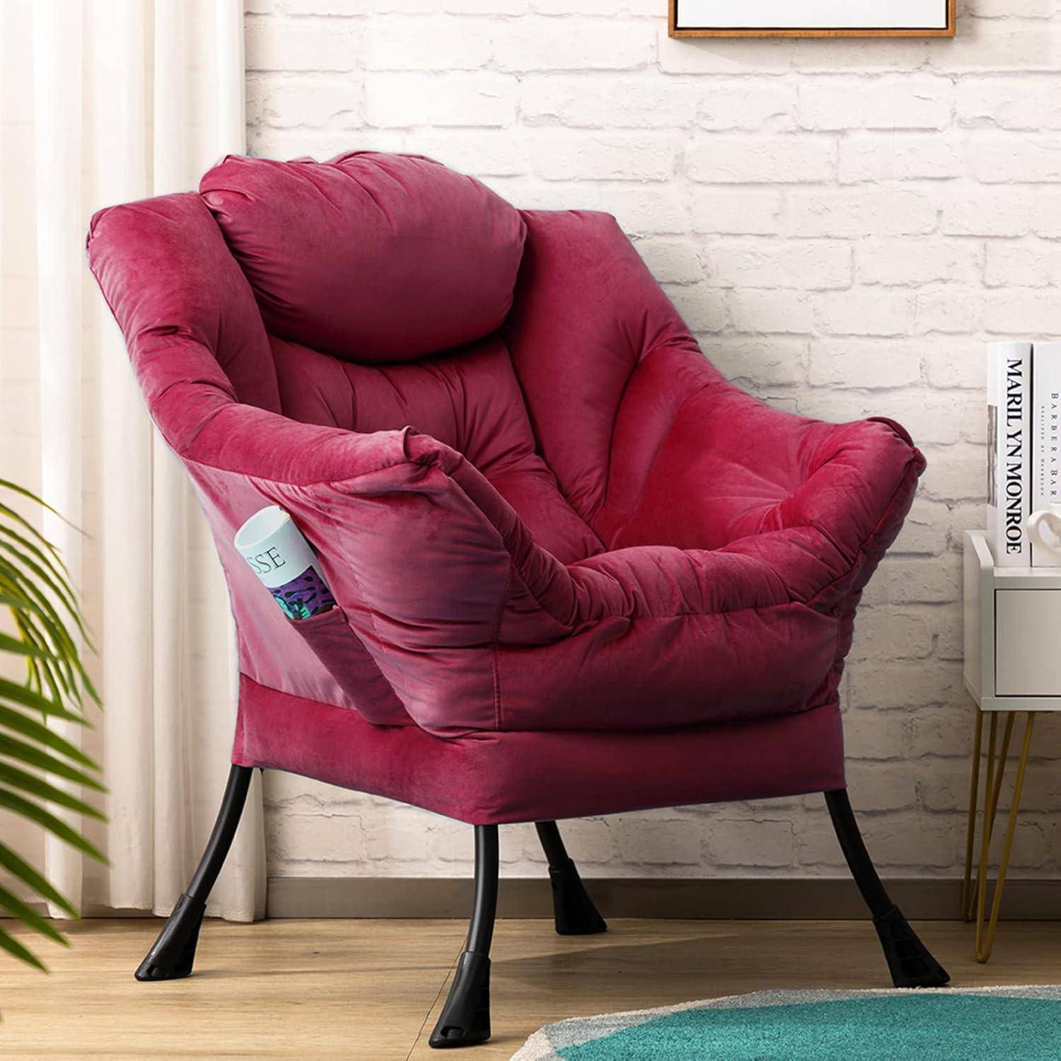 Ein plüschiger Magenta-Sessel mit schwarzen Beinen sitzt in einem hellen Raum an einer weißen Backsteinwand, neben einem Beistelltisch mit Büchern.