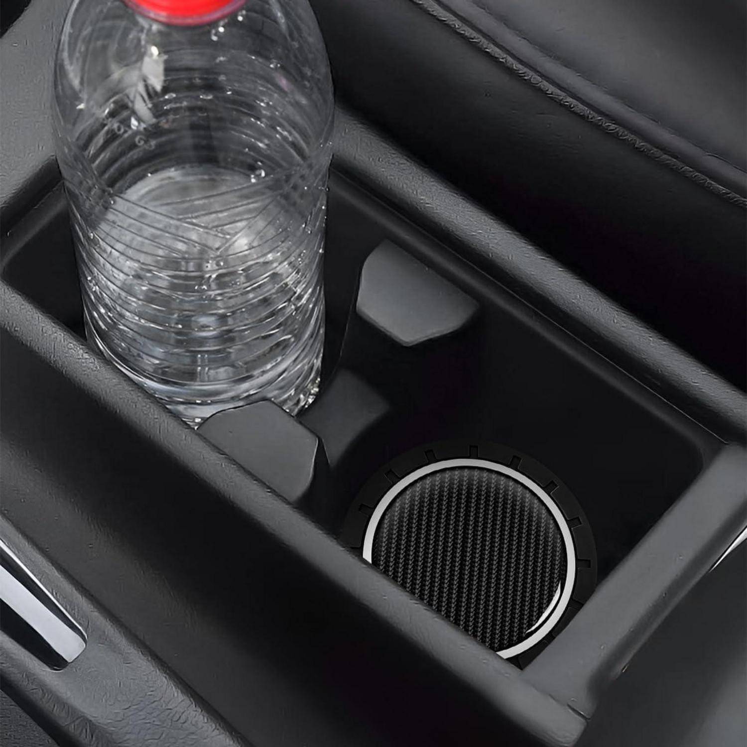 Getränkehalter im Auto mit einer durchsichtigen Kunststoff-Wasserflasche neben einem runden Lautsprechergitter in der Mittelkonsole.