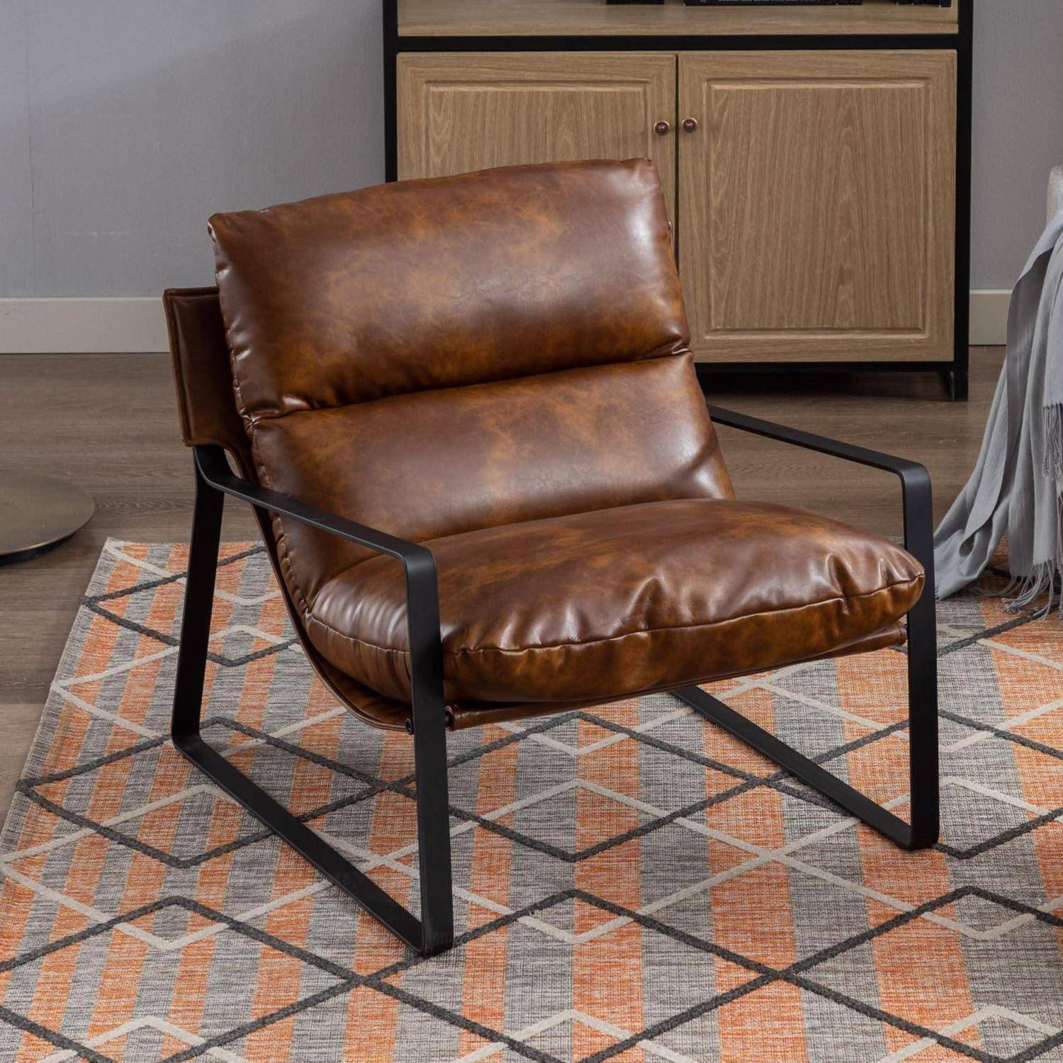 Brauner Ledersessel mit schwarzem Metallrahmen auf einem geometrischen Teppich in einem modernen Wohnzimmer.