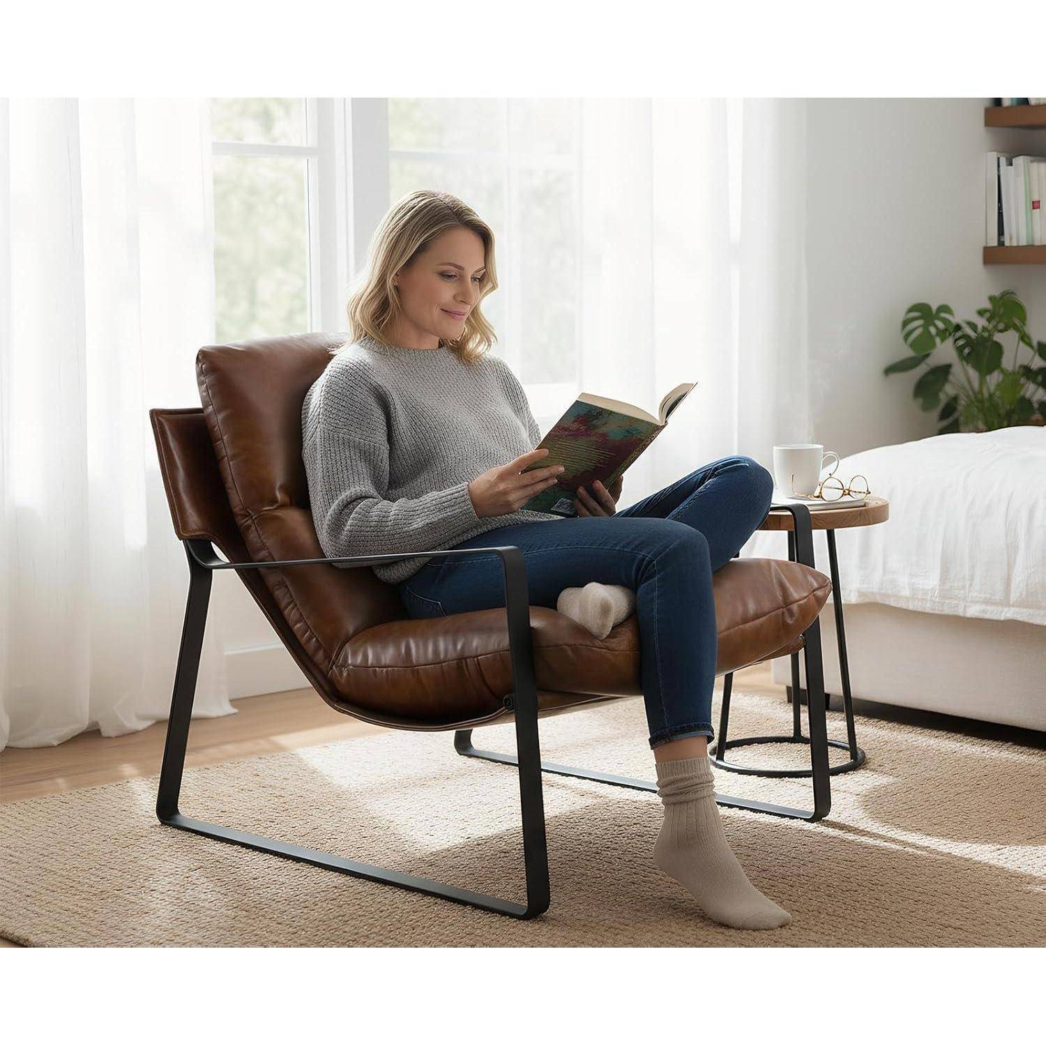 Eine Frau liest ein Buch in einem braunen Lederstuhl neben einem kleinen Tisch mit einer Tasse in einem hellen Schlafzimmer.