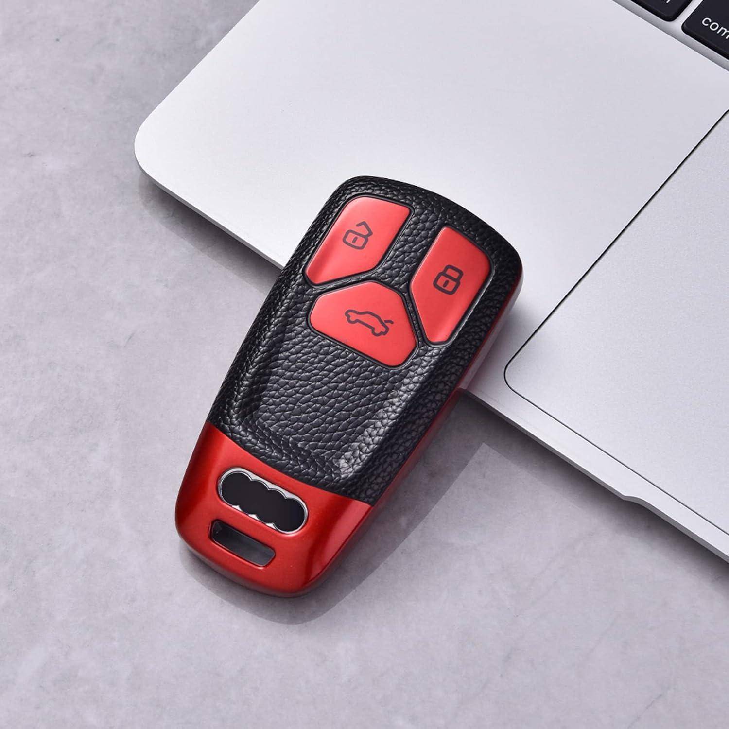 Rot-schwarze Autoschlüssel-Fernbedienung mit Verriegelungs-, Entsperrungs- und Kofferraumtasten, die neben einem Laptop auf einer grauen Oberfläche liegen.