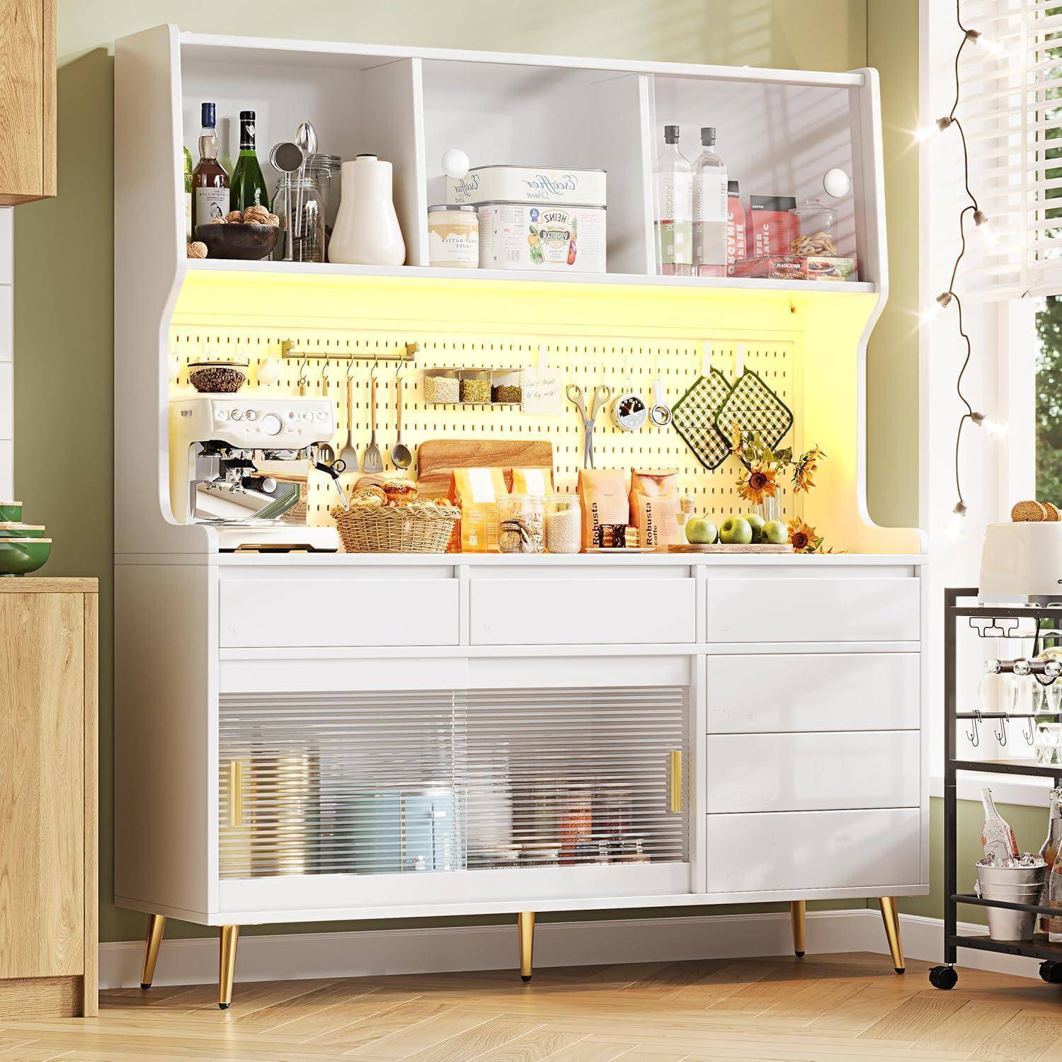 Ein modernes weißes Küchenbuffet mit offenen Regalen, Lochblech-Speicherung und warmer Beleuchtung unter den Regalen zeigt Geschirr, Flaschen, Gläser und Obst.