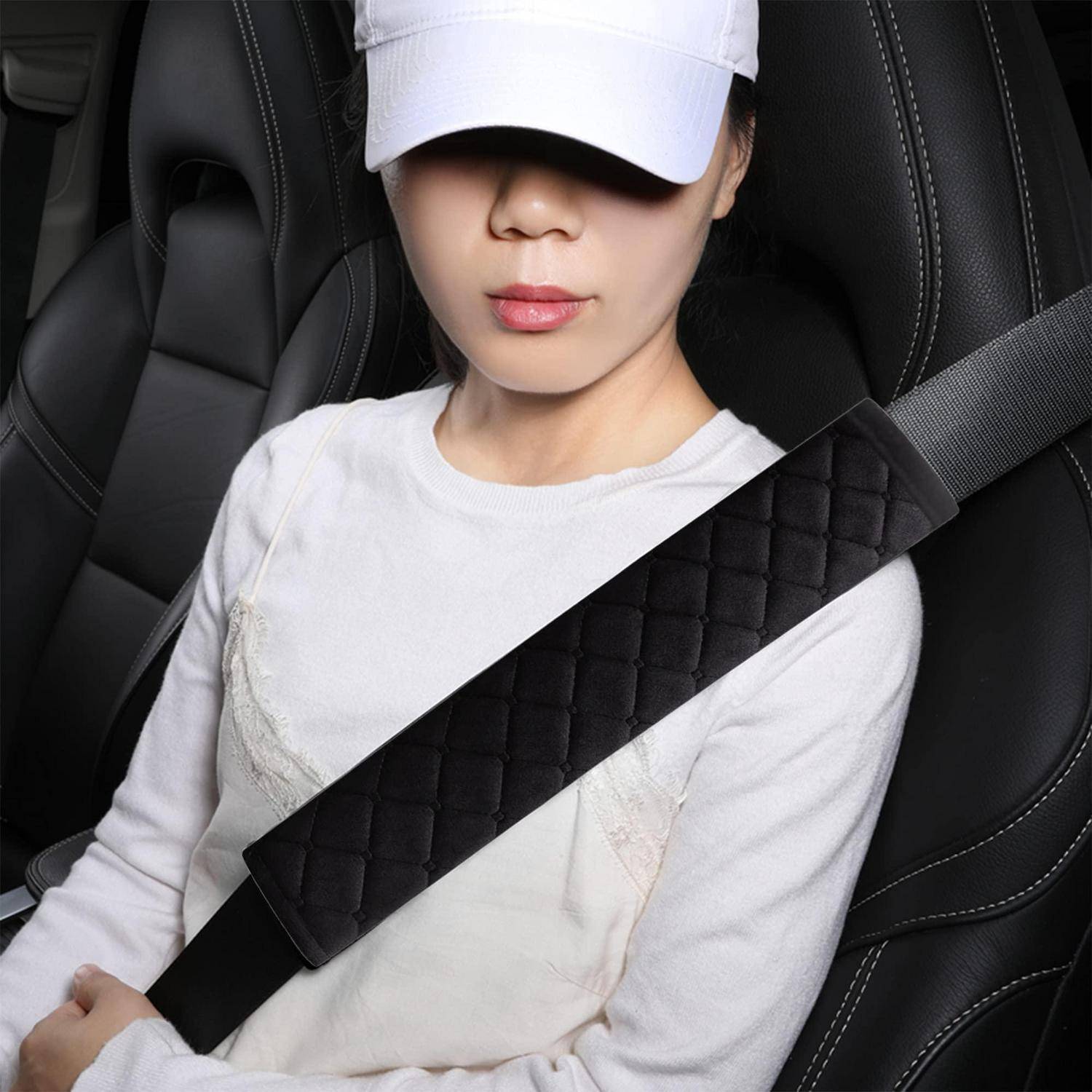 Nahaufnahme einer Person, die in einem Auto sitzt, eine weiße Mütze und ein weißes Hemd trägt, mit einem über die Brust gespannten Sicherheitsgurt.