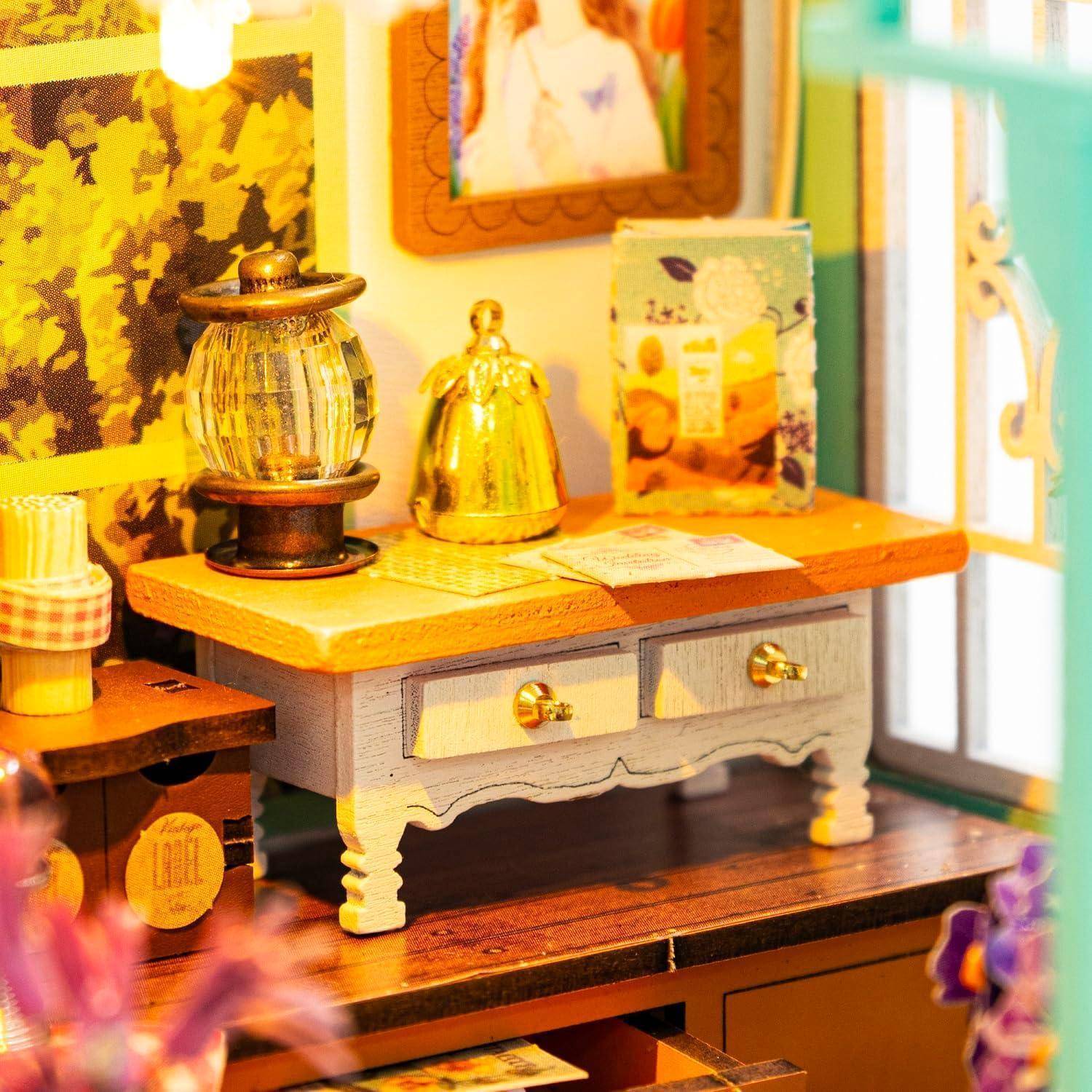 Miniatur-Tischplatte-Display eines rustikalen Waschtisches oder Sideboards mit zwei Schubladen, einer Laterne, einer goldenen Glocke und kleinen Dekorationsgegenständen neben einem Fenster.