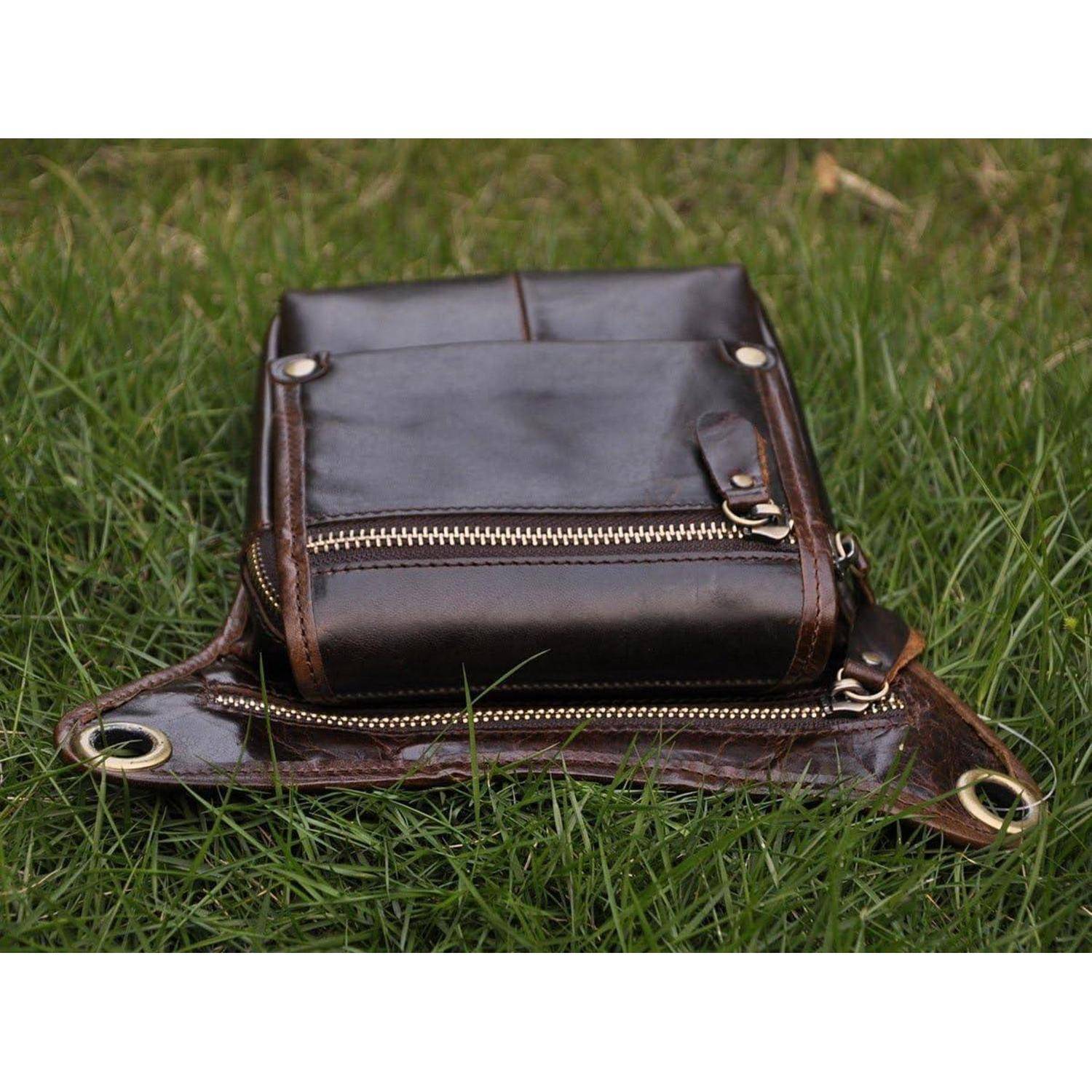 Braune Ledertasche zum Umhängen mit mehreren Reißverschlusstaschen, liegt auf Gras im Freien.