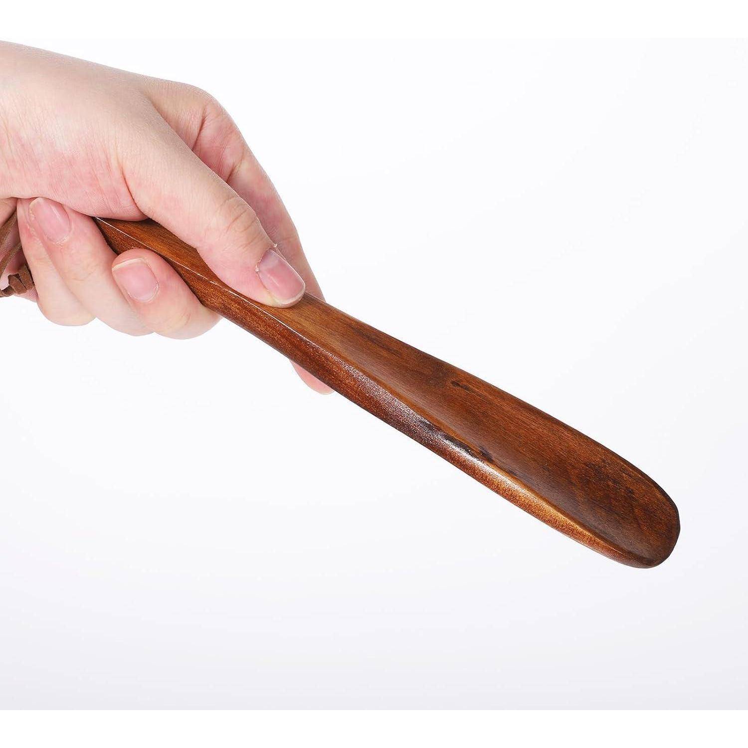 Hand, die einen Schuhlöffel aus Holz auf einem einfachen weißen Hintergrund hält.