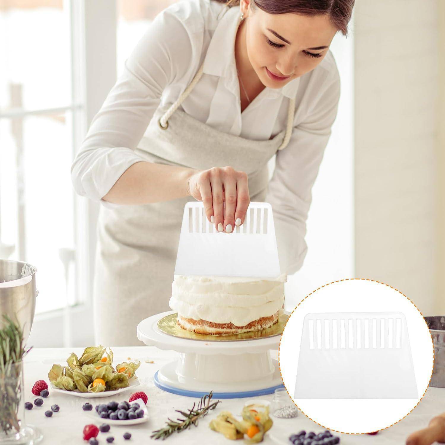Frau in Schürze, die Glasur auf einem mehrschichtigen Kuchen mit einem weißen Glättwerkzeug für Zuckerguss glättet, mit einer Detailaufnahme des Werkzeugs