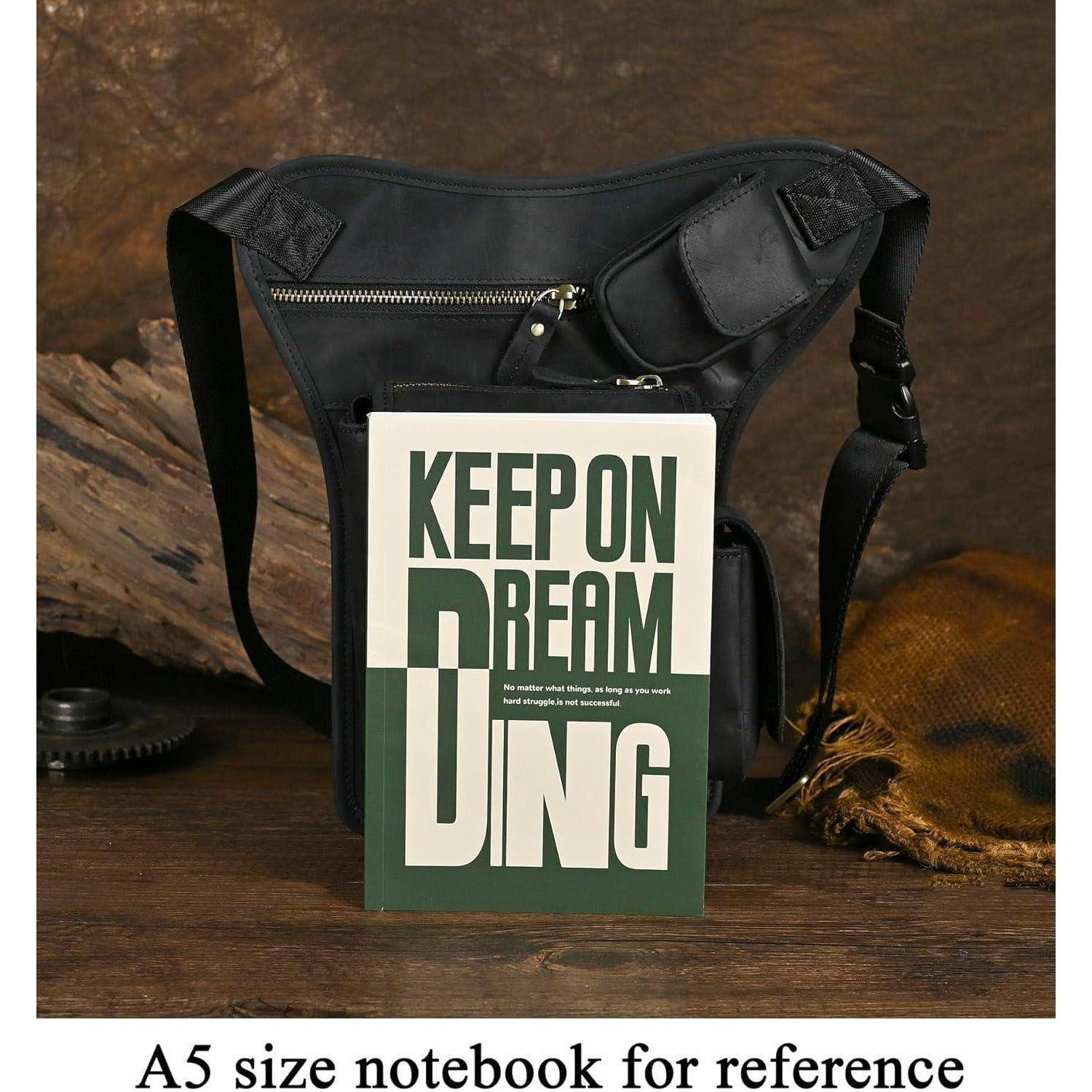 Ein A5-Notizbuch mit dem Coverbext „KEEP ON DREAMING" steht vor einer schwarzen Umhängetasche auf einer Holzoberfläche.