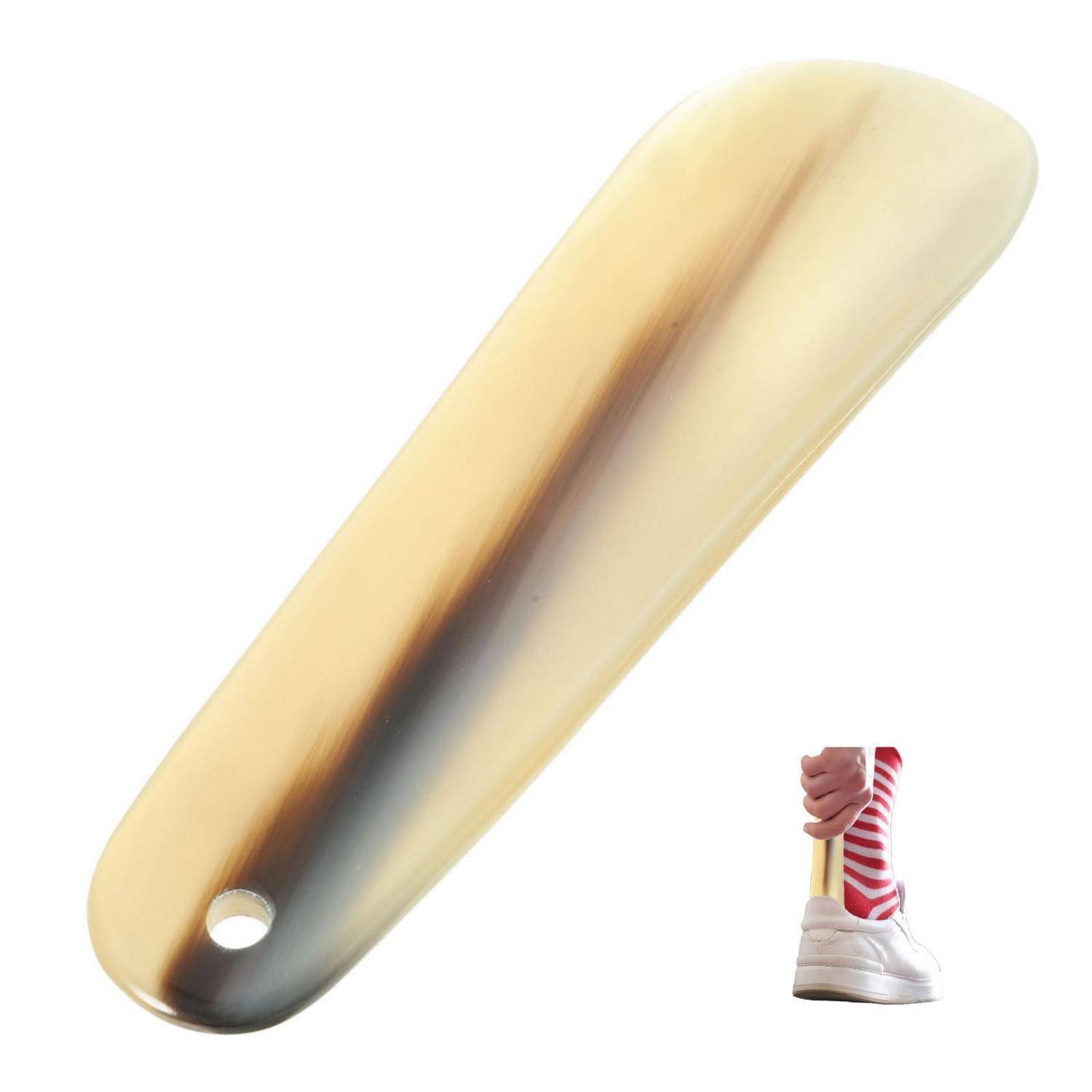 Ein goldtoniger Metallschuhlöffel mit einem Aufhängeloch, abgebildet neben einer Hand, die ihn am Griff hält, um die Größe zu zeigen.