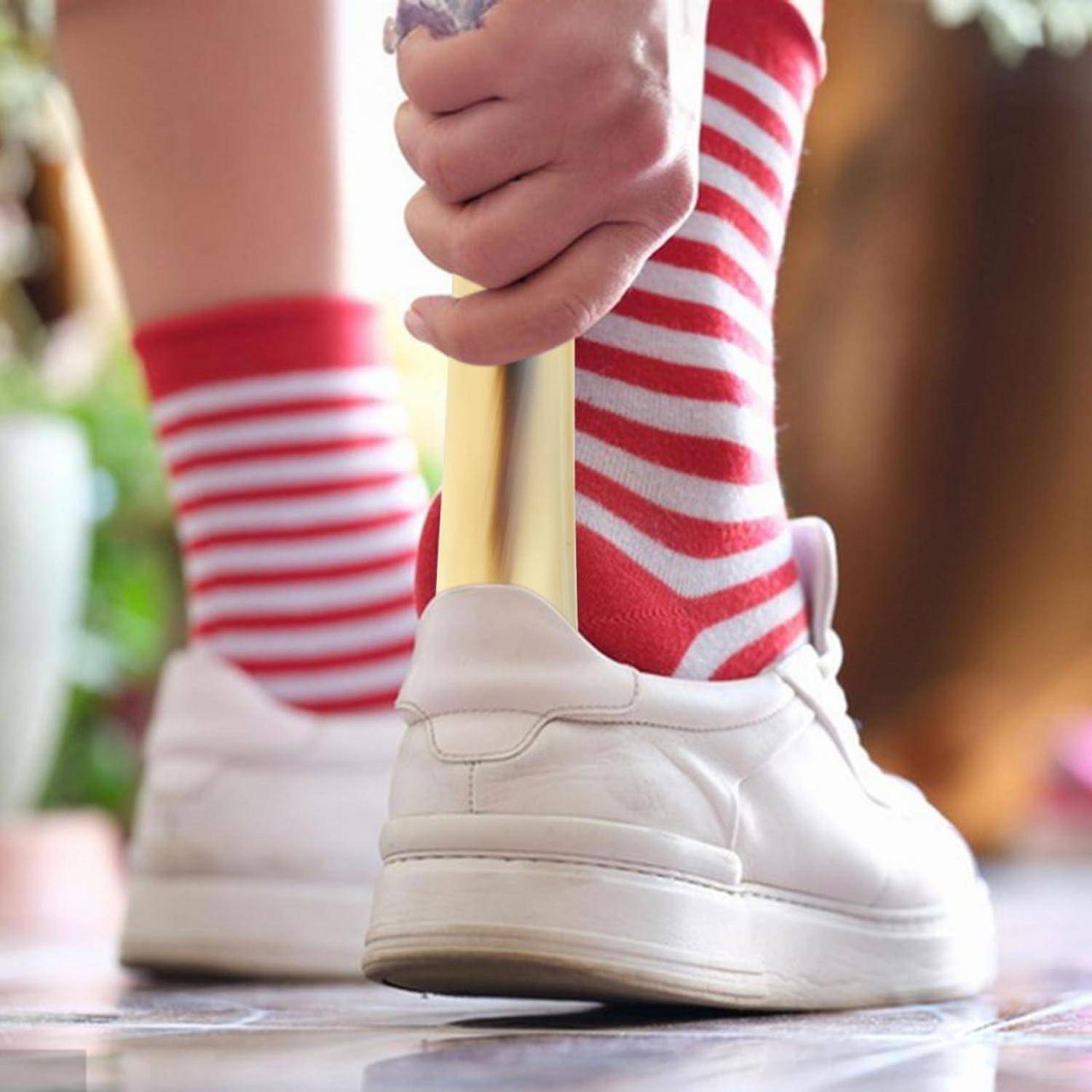 Nahaufnahme eines Kindes, das in weißen Sneakern und rot-weiß gestreiften Socken läuft und sich an einem goldenen Griff zur Unterstützung festhält.