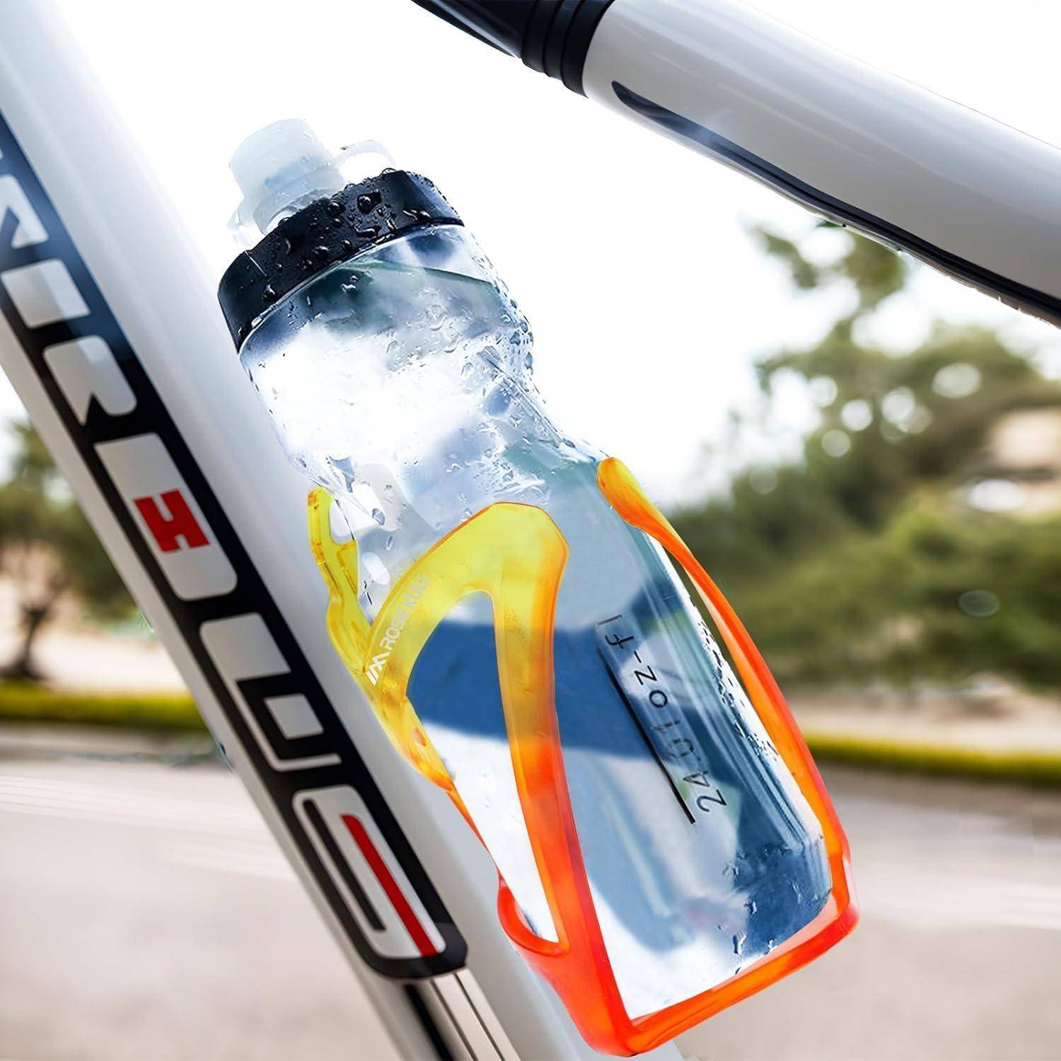 Transparente Kunststoff-Wasserflasche mit orangefarbenem Halter, der am Fahrradrahmen montiert ist, wahrscheinlich zur Flüssigkeitszufuhr während des Fahrens.