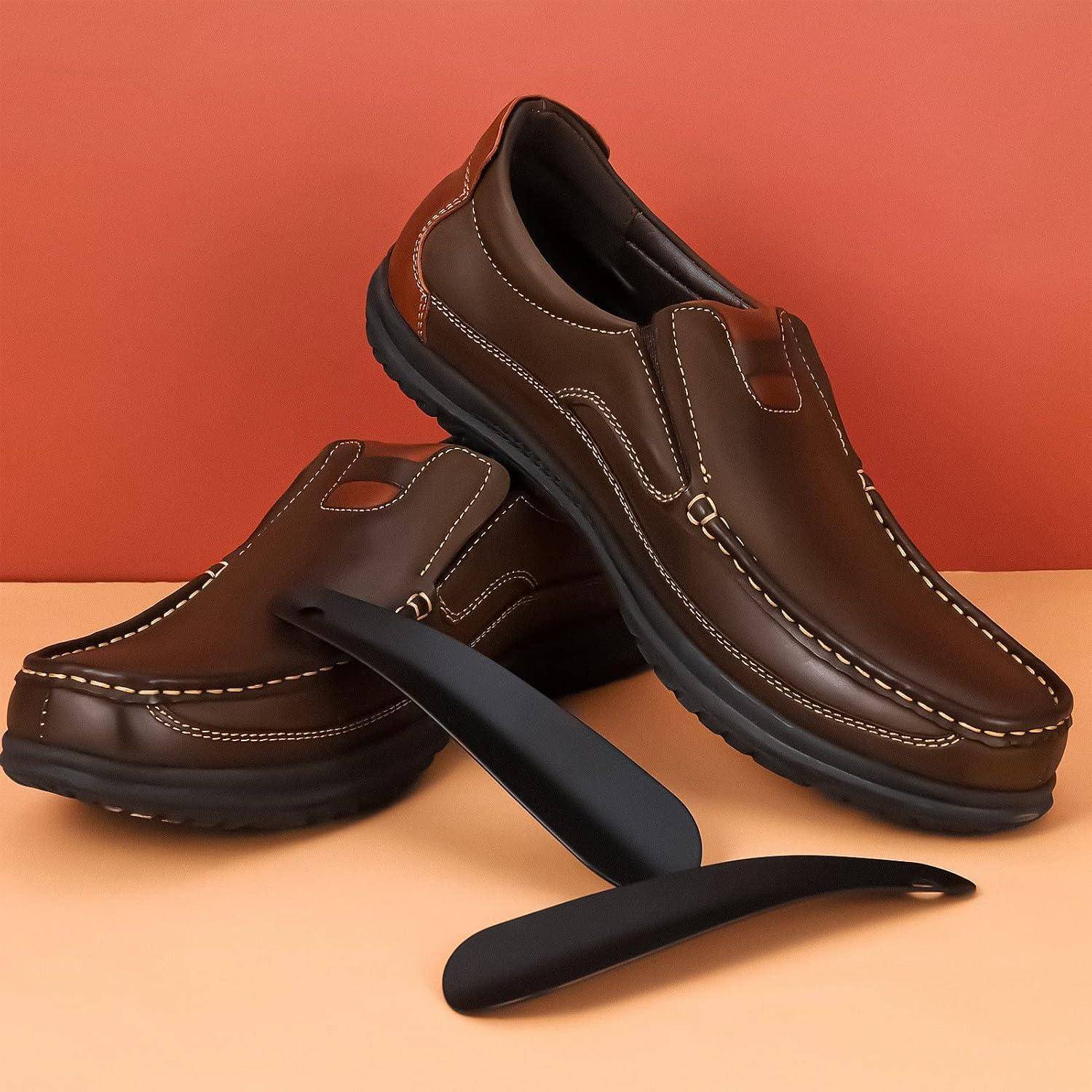 Braune Slipper-Loafer mit weißer Naht, gezeigt mit abnehmbaren schwarzen Fußgewölbestützen auf einem Pfirsich- und orangefarbenen Hintergrund.