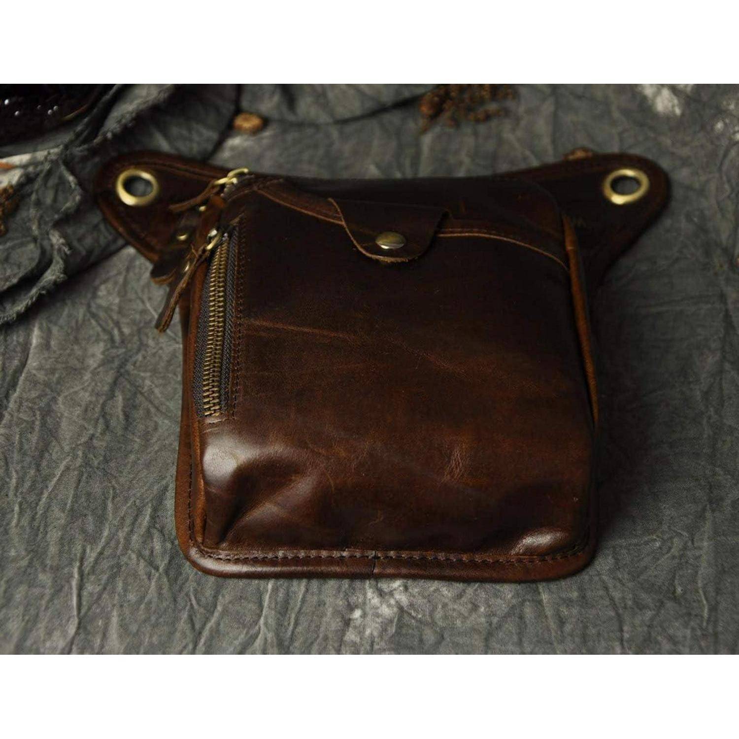 Braune Ledertasche mit Reißverschluss und Klettverschluss-Klappe, gezeigt auf einer grauen strukturierten Oberfläche.