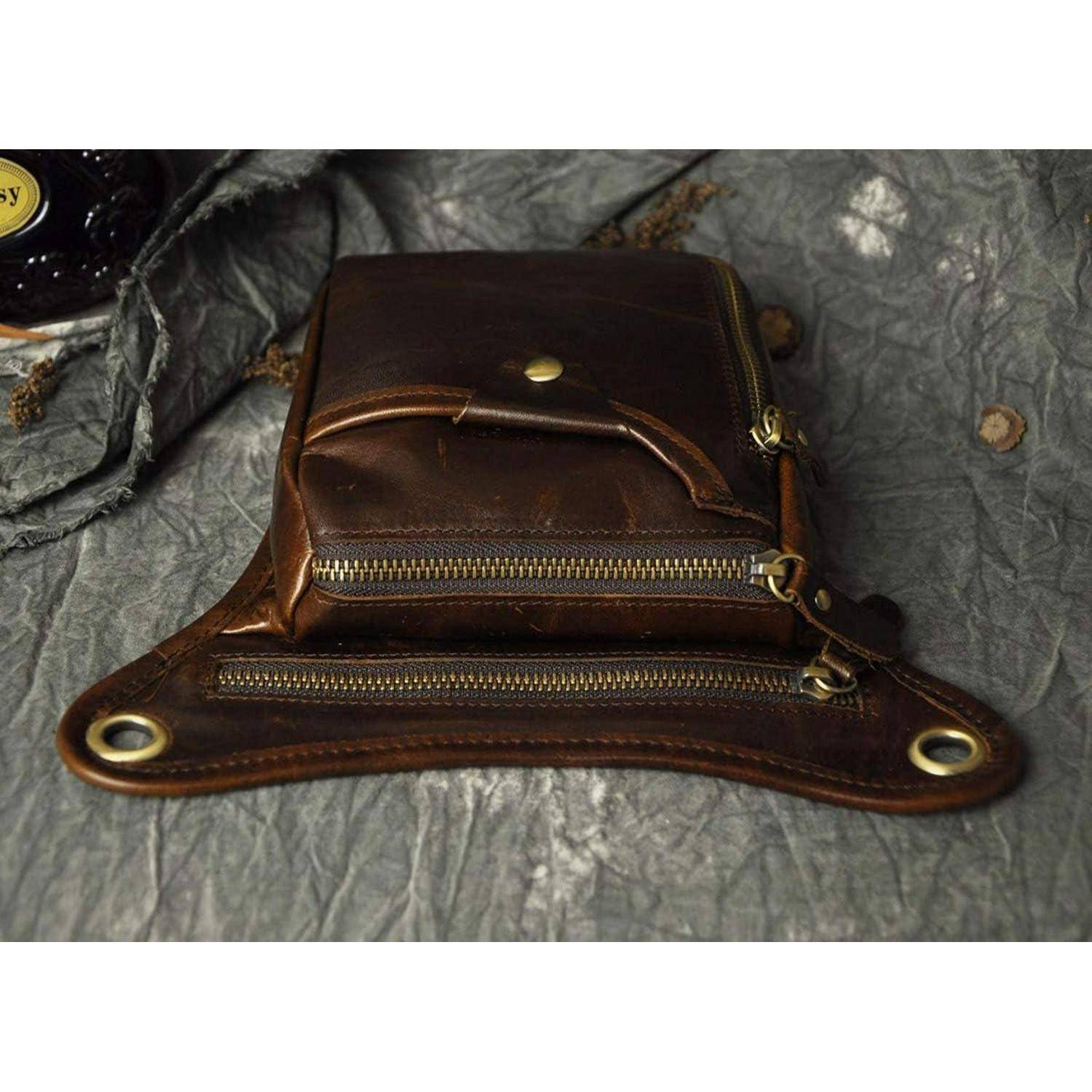 Braune Ledertasche für die Taille mit mehreren Reißverschlusstaschen und Metallaösen, gezeigt auf einer zerknitterten grauen Oberfläche.