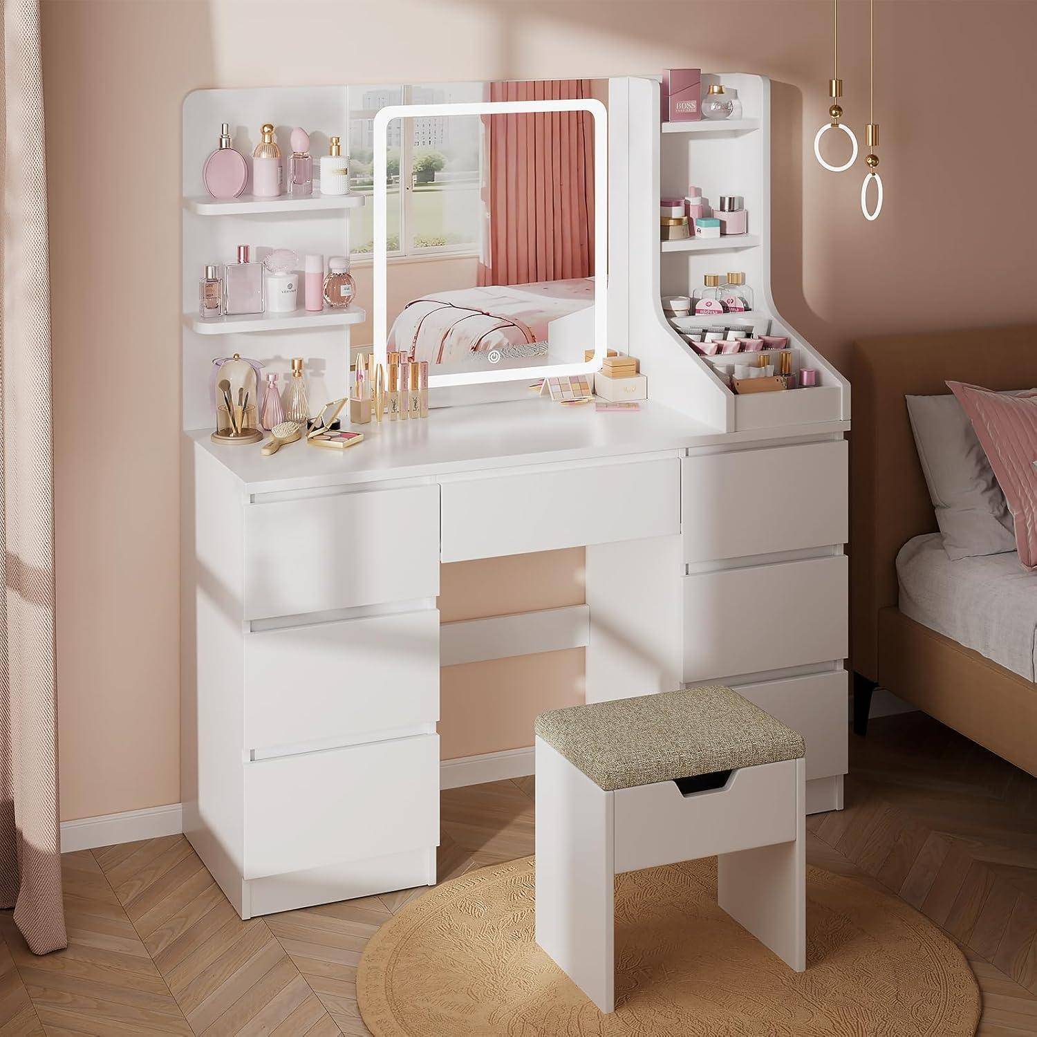 Weißer Frisiertisch mit Spiegel, Regalen, Schubladen und passendem Hocker in einem Schlafzimmer in Pastellfarben, angeordnet mit Kosmetika und Dekoration.