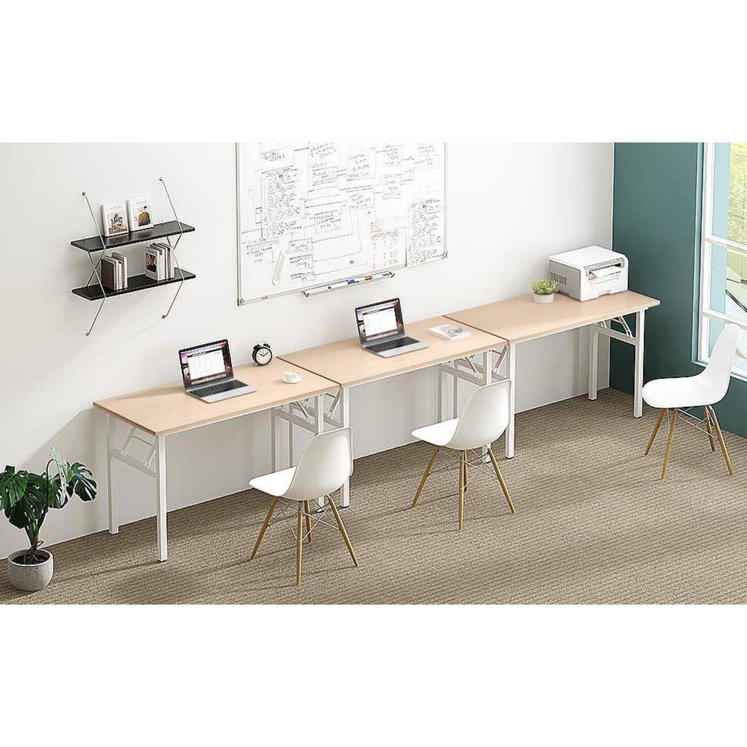 Heller gemeinsamer Arbeitsbereich mit drei Schreibtischen, zwei Laptops, Stühlen, Wandregalen, Whiteboard und einem Drucker in der Nähe eines Fensters.