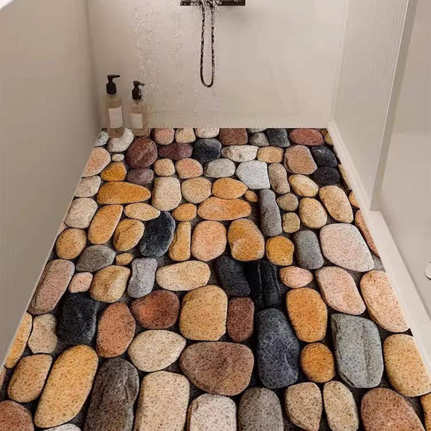 Badezimmerduschieboden mit einer Kieselstein-Muster-Matte bedeckt, mit Duschflaschen im Hintergrund und Wasser, das von oben herabfällt.