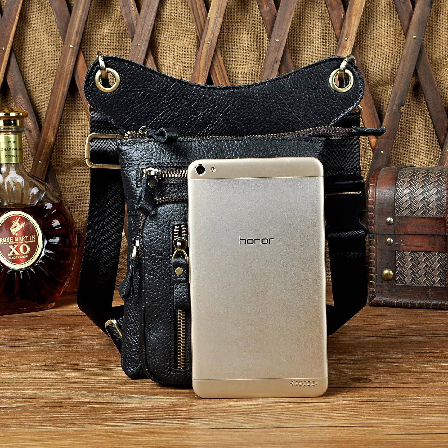 Silber-farbiges Honor-Smartphone, das an einer schwarzen Ledertasche auf einem Holztisch lehnt, flankiert von einer Cognacflasche und einer dekorativen Schatulle.