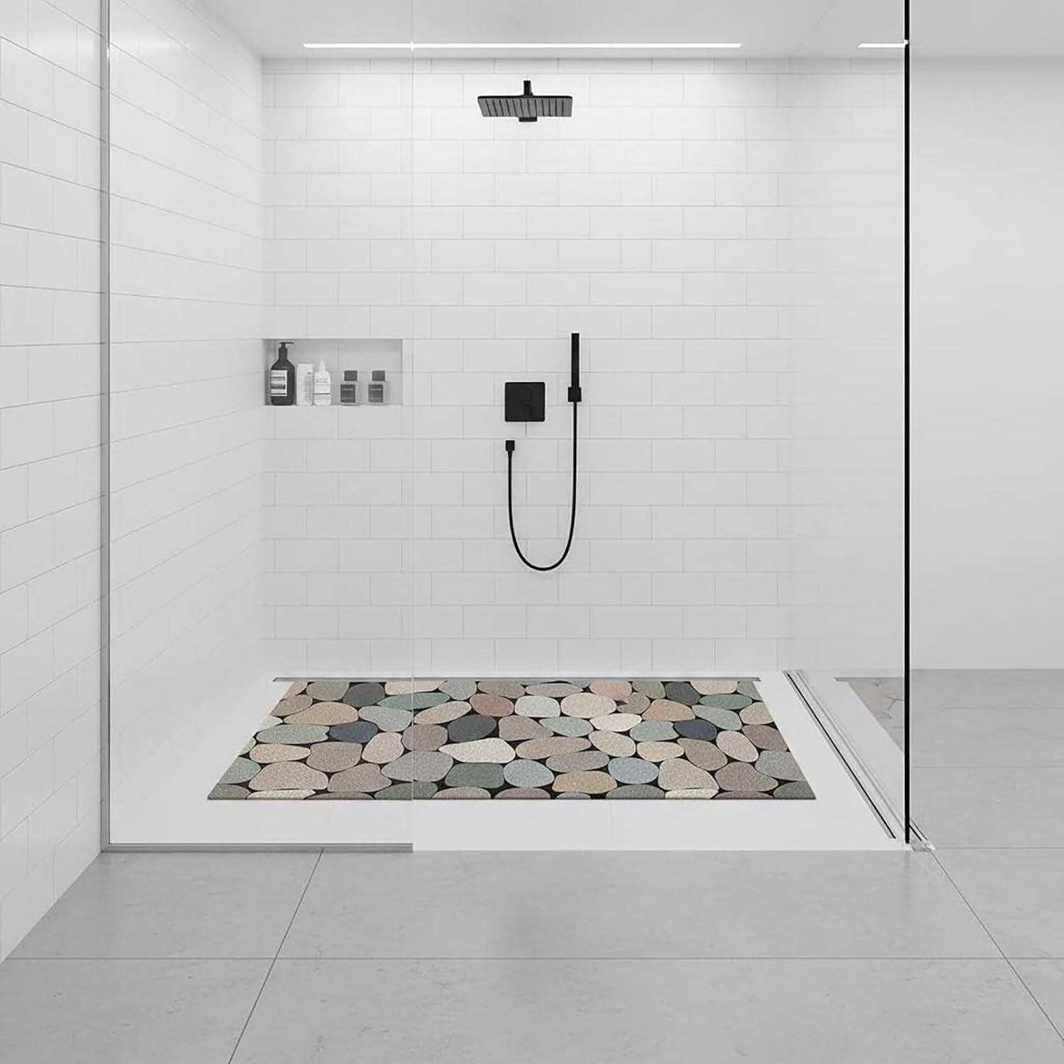 Minimale, weiß geflieste Dusche mit Regenduschkopf, Handbrause, Flaschenablage in der Nische und Kieselsteinmatte hinter einer Glastrennwand.