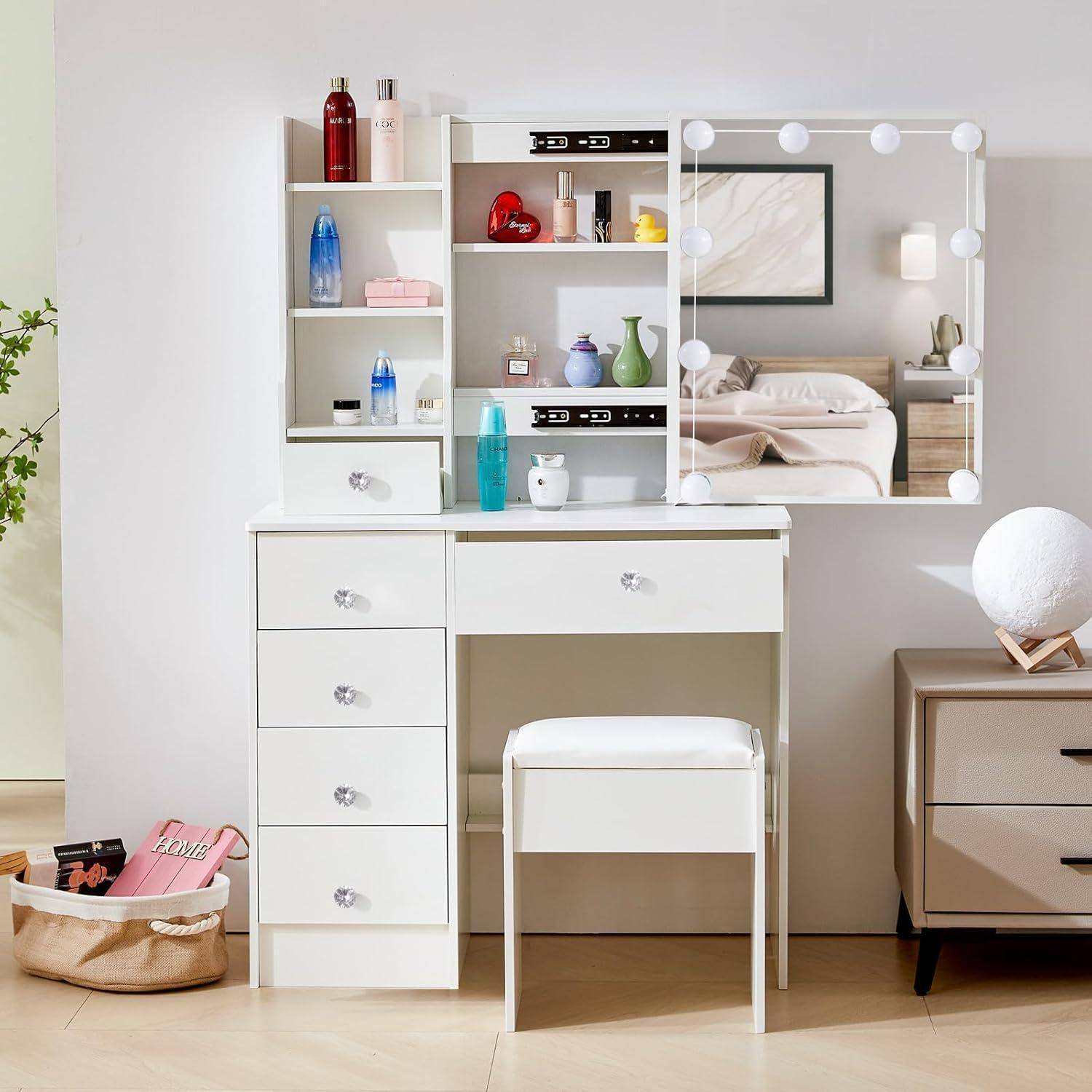 Weißer Frisiertisch mit Spiegellicht, Schubladen, Regalen und Hocker in einem Schlafzimmer; Kosmetik und Dekoration ausgestellt, mit Bett im Spiegel reflektiert.